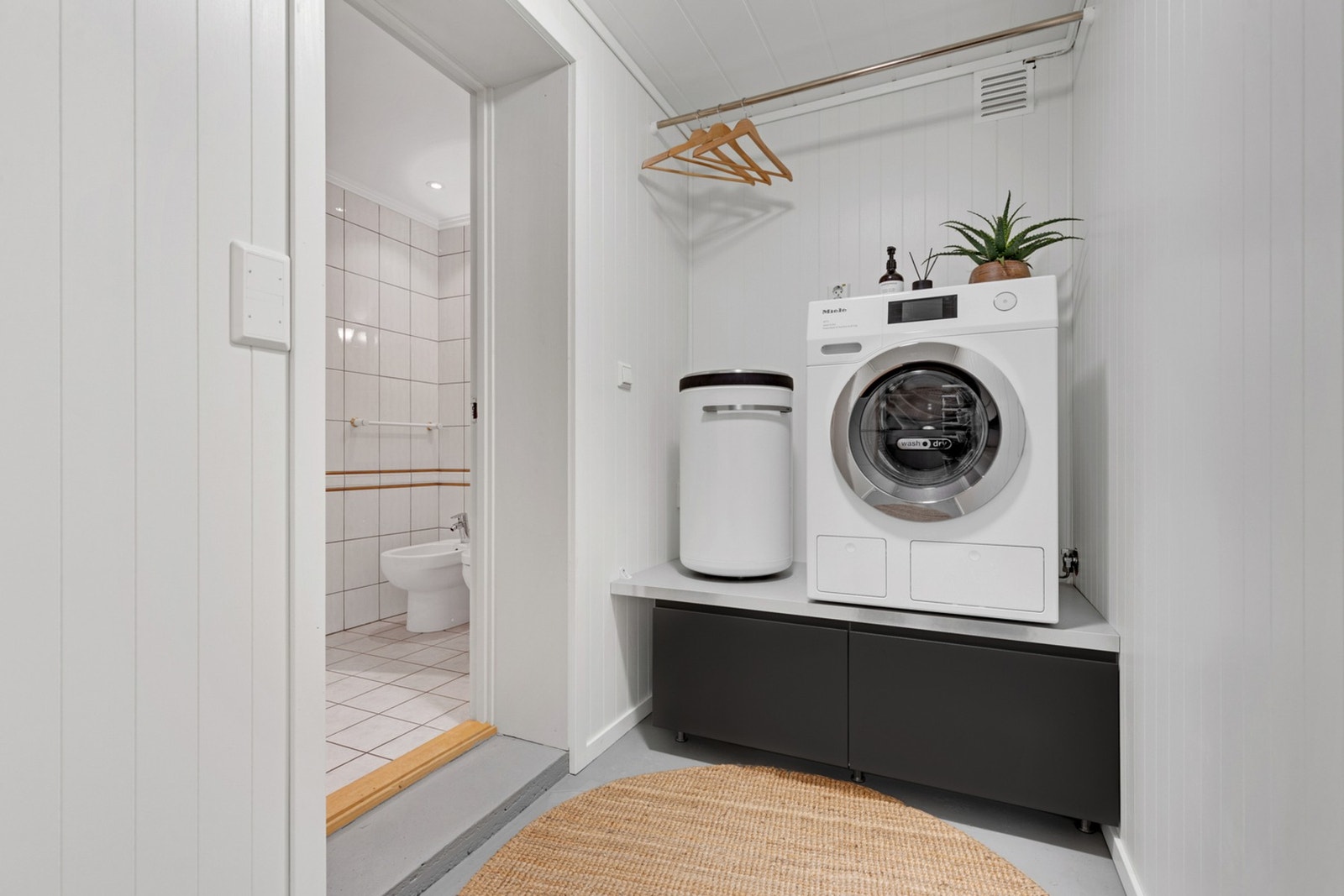 Mellomgang med plass til vaskemaskin. Innenfor vaskerommet ligger en bod/garderobe med varmelist til tørking av klær og sko. Galleribilde