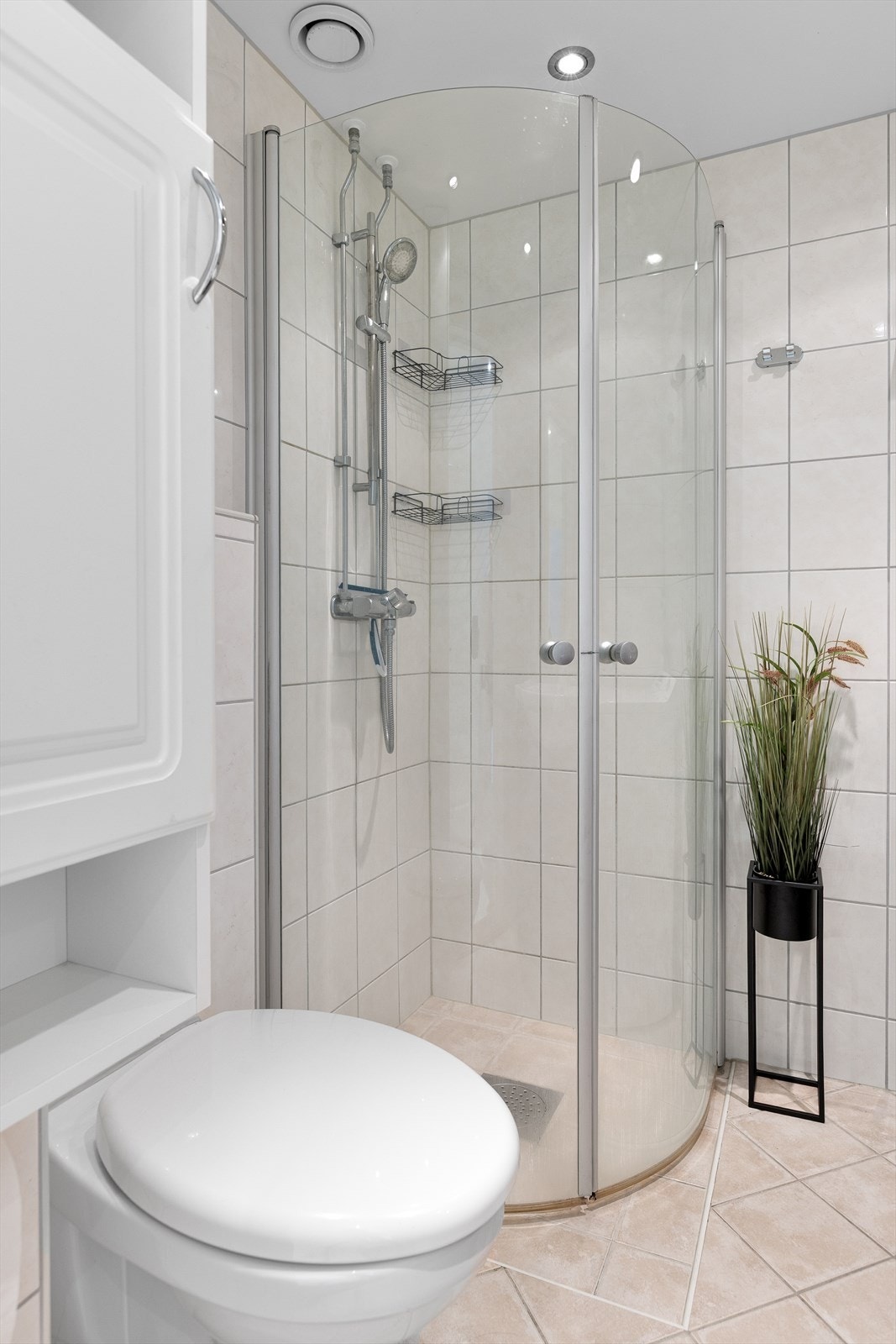 Badet er utstyrt med vegghengt toalett og dusjhjørne med glassdører Galleribilde