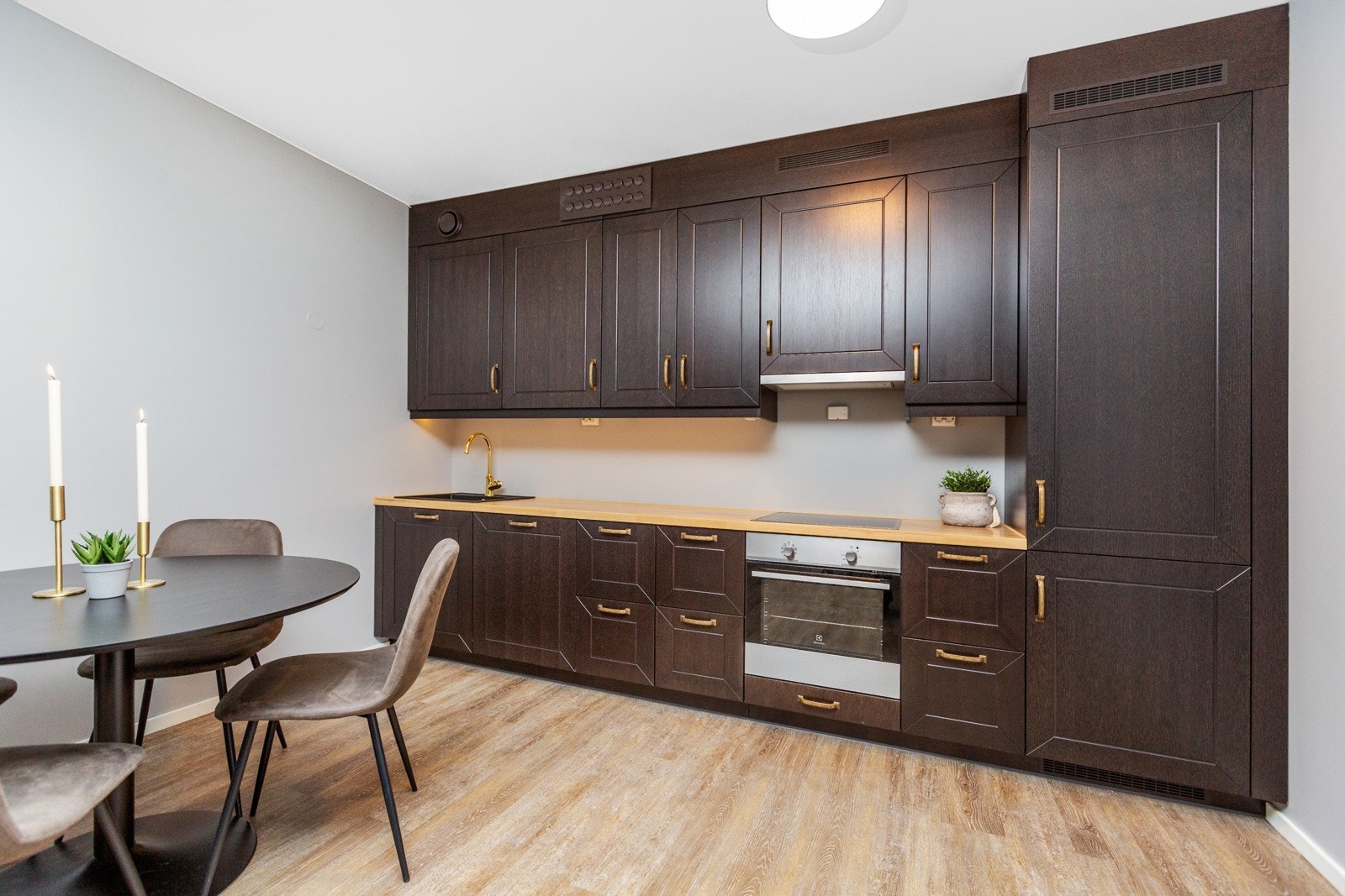 Benkeplate i Ask heltre, med nedfelt sort kum med ettgreps blandebatteri i messing. Kjøkkenet har integrerte hvitevarer, herunder keramisk platetopp, stekeovn, oppvaskmaskin, kjøl-/fryseskap og avtrekksvifte Galleribilde