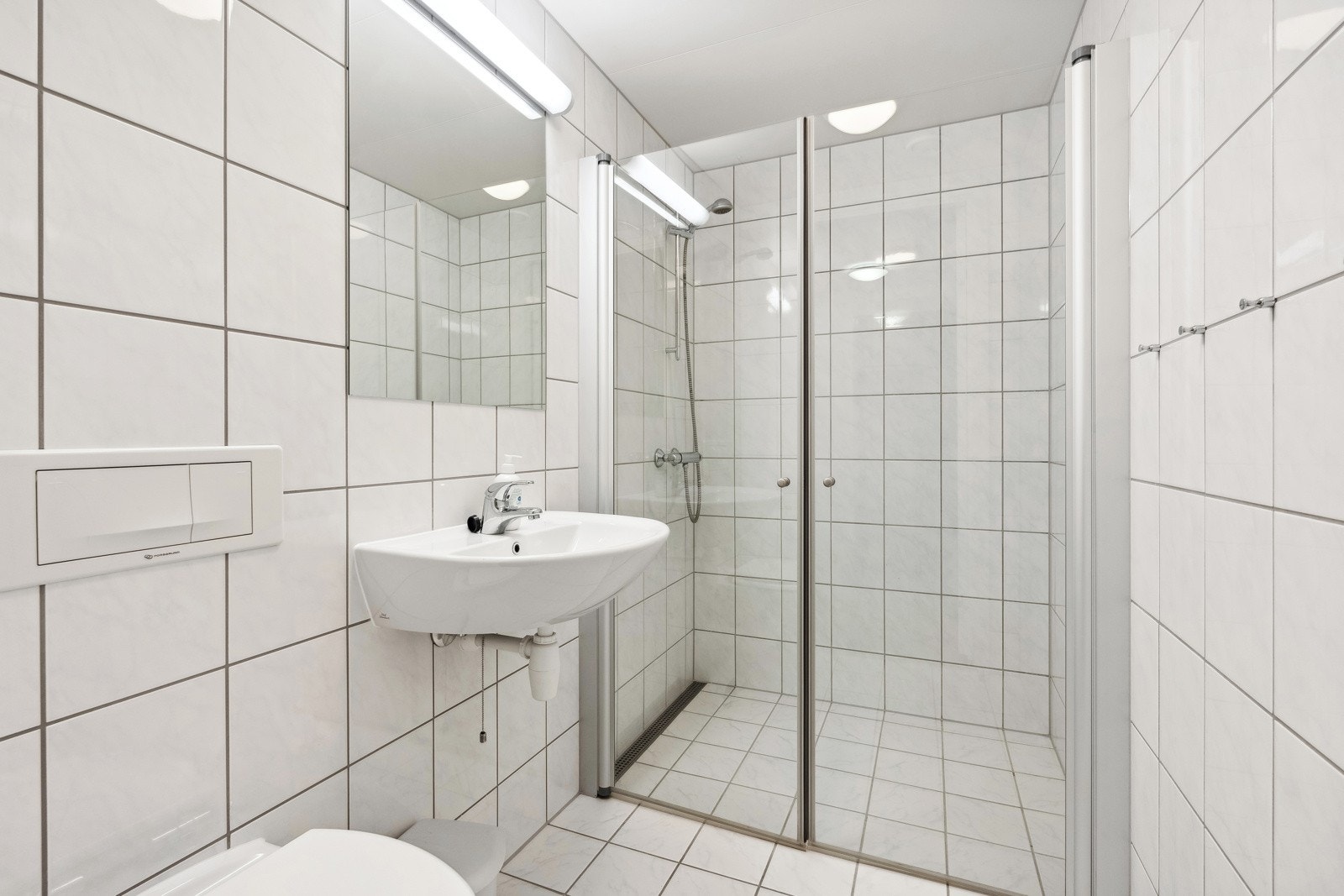 Det tredje badet ligger i tilknytning til entreen og har lyse fliser på gulv og vegger, elektrisk gulvvarme, dusjnisje, wc og servant. Galleribilde