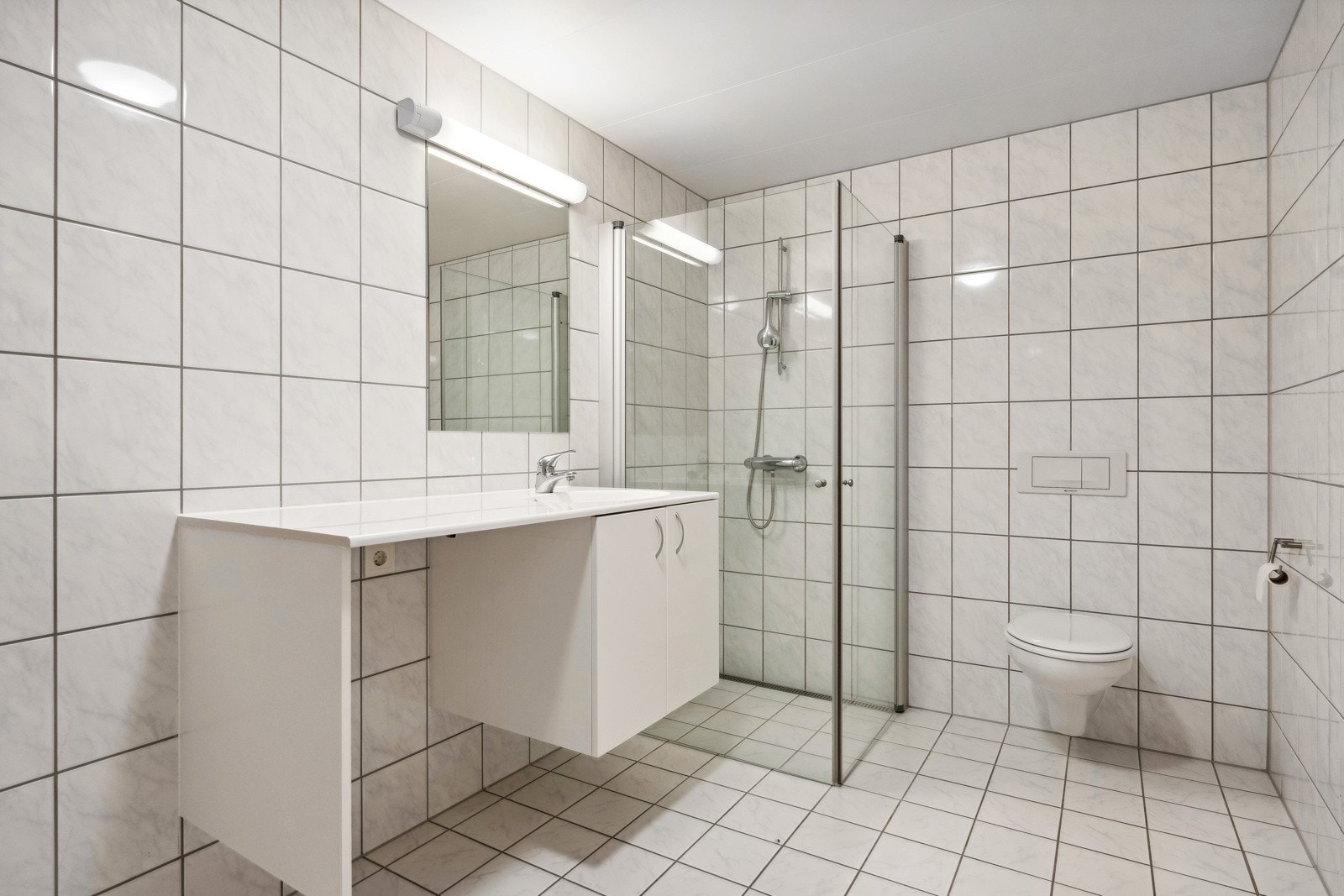 Leiligheten har tre lyse og pene baderom med bl.a. dusjnisje, wc, servant og elektrisk gulvvarme. Dette badet har også opplegg for vaskemaskin under benk. Galleribilde