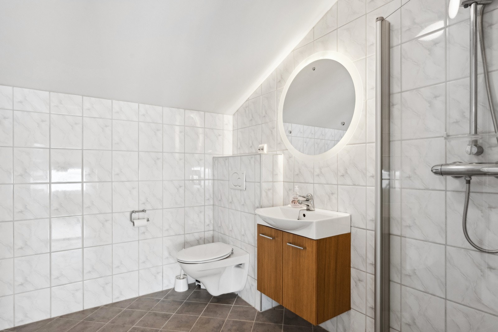 Badet i overetasjen har pene fliser på gulv og vegger, samt dusjnisje, wc og servant. Galleribilde