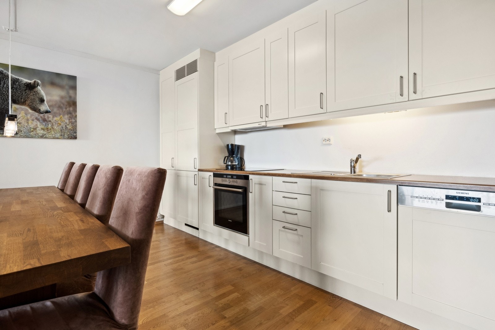 Kjøkkenet har en flott innredning med lyse rammefronter, benkeplate i laminat og integrerte hvitevarer fra Siemens. Galleribilde