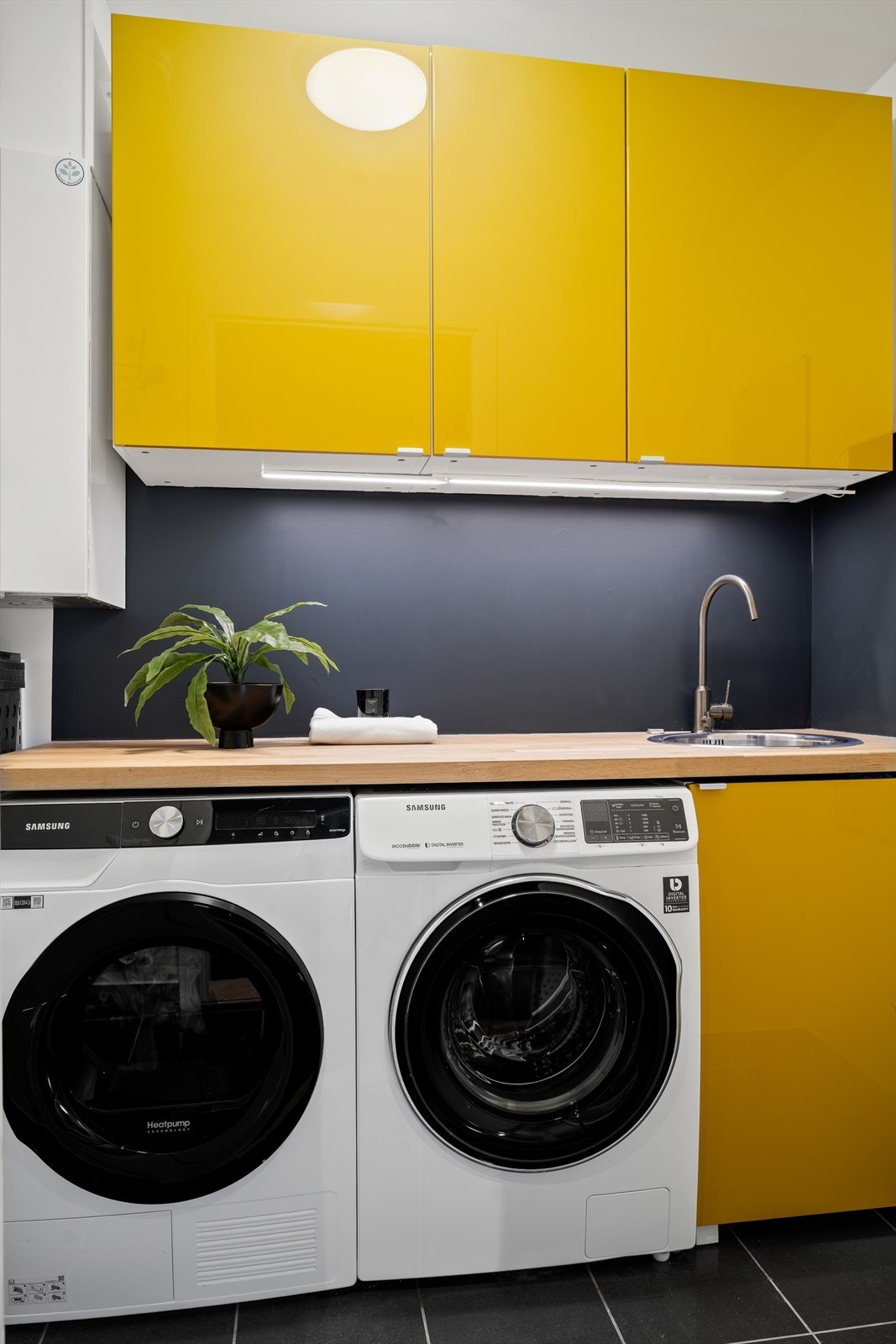 Praktisk separat vaskerommet med flislagt gulv med vannbåren varme, utstyrt med servant og har opplegg for vaskemaskin og tørketrommel. Galleribilde