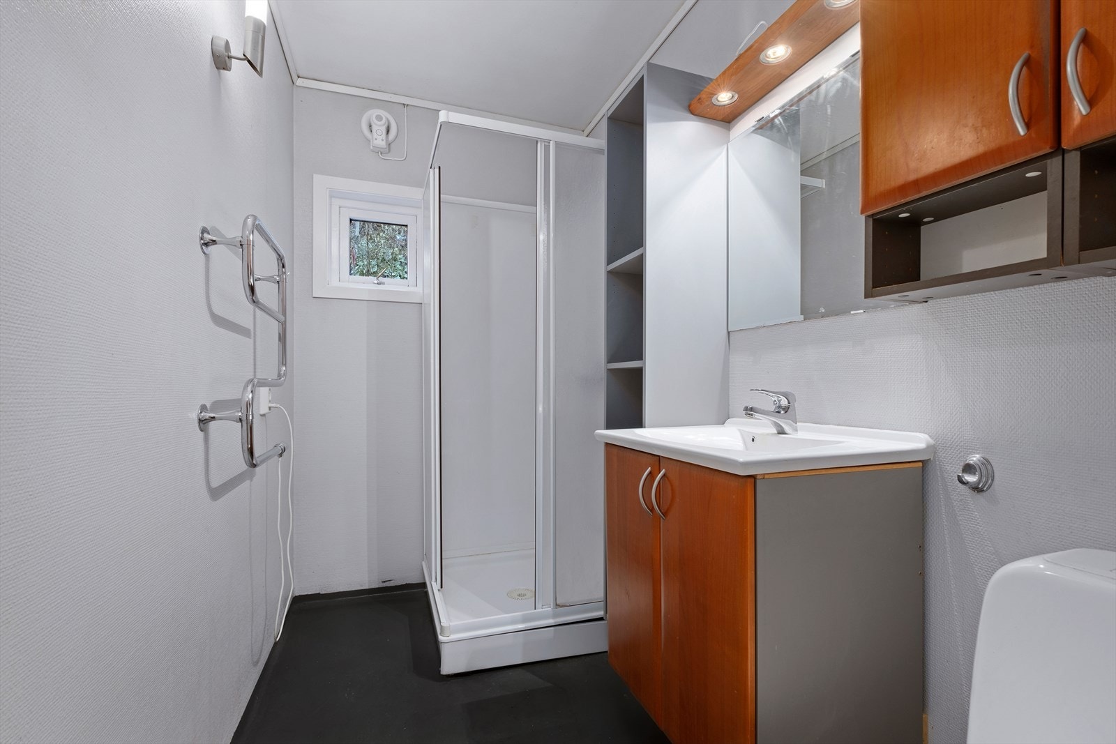 Badet består av under- og overskap, dusjkabinett og toalett. Galleribilde