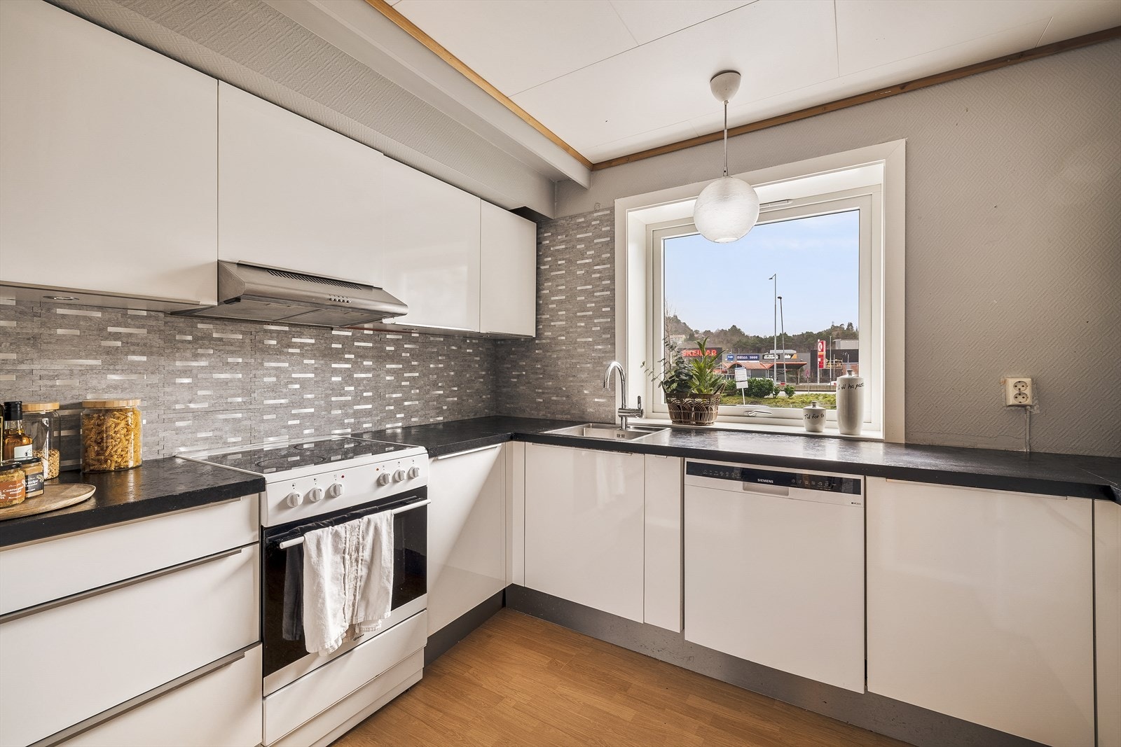 Pent kjøkken med hvite slette fronter og god benk- og skapplass Galleribilde