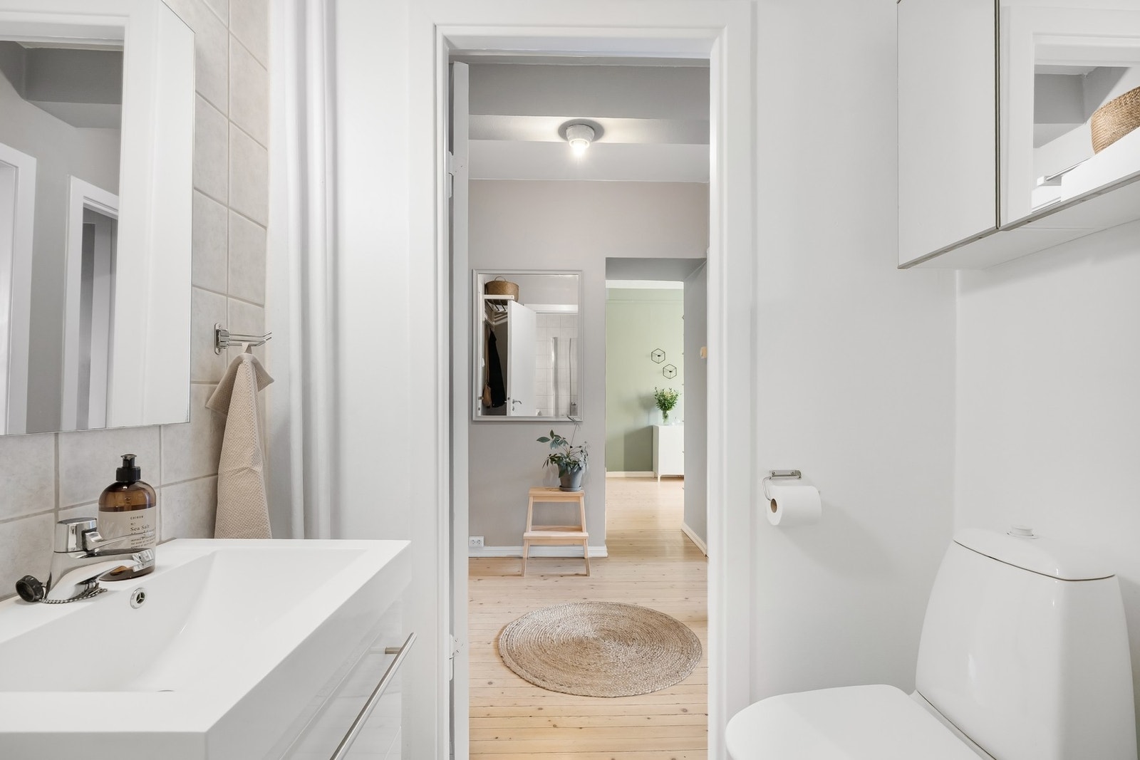 Moderne baderomsinnredning med skuffer for oppbevaring og vegghengt speilskap over toalett for ytterligere oppbevaring. Galleribilde