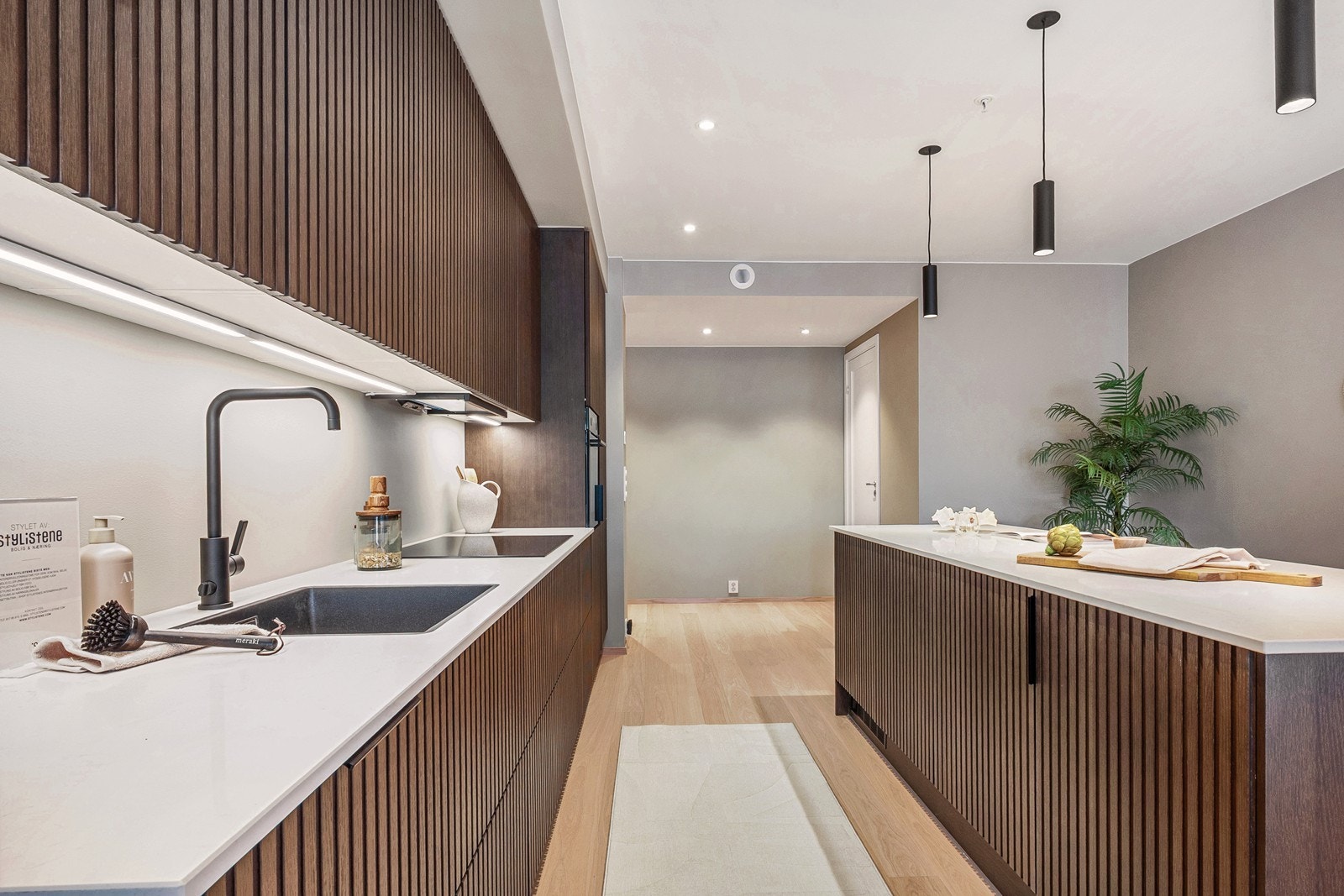 Kompositt benkeplate fra Caesarstone i modell Frosty Carinna skaper en fin kontrast til det mørke treverket, mens den sorte kjøkkenkranen fra Tapwell tilfører et moderne preg. Ekstra kurs er lagt opp til mikro, kaffemaskin eller Quooker. Galleribilde