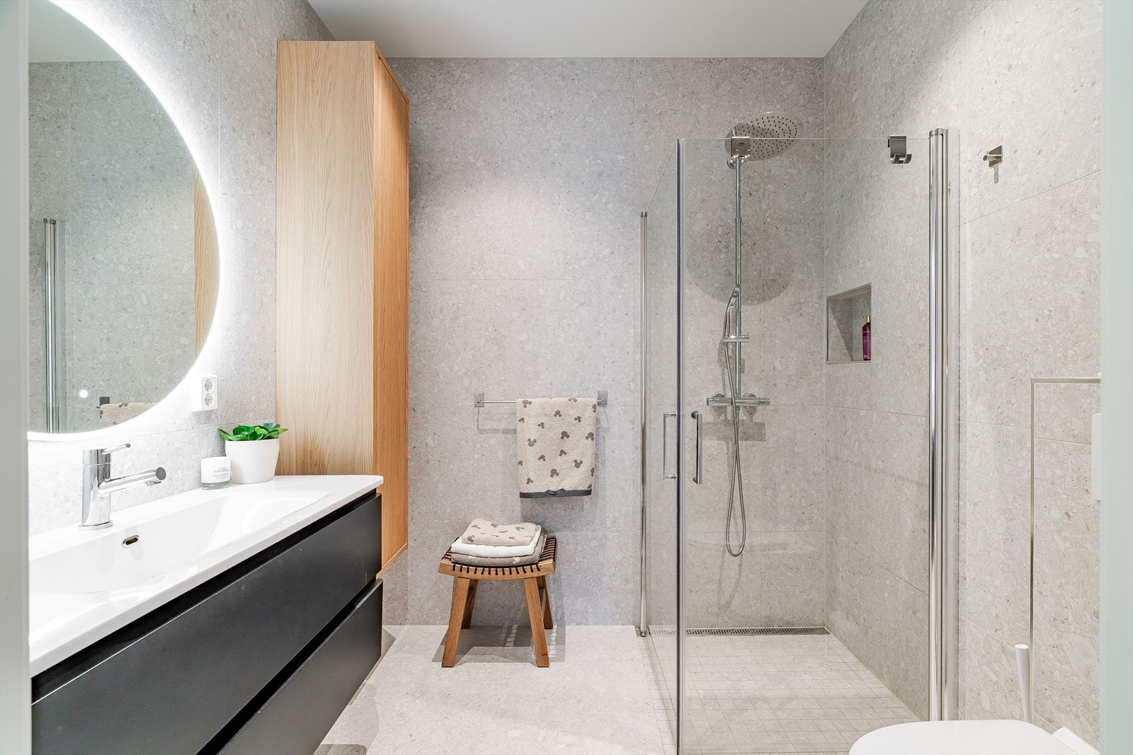 Stilrent bad med store fliser, regndusj, innfellbar dusjdør og vegghengt toalett. Galleribilde