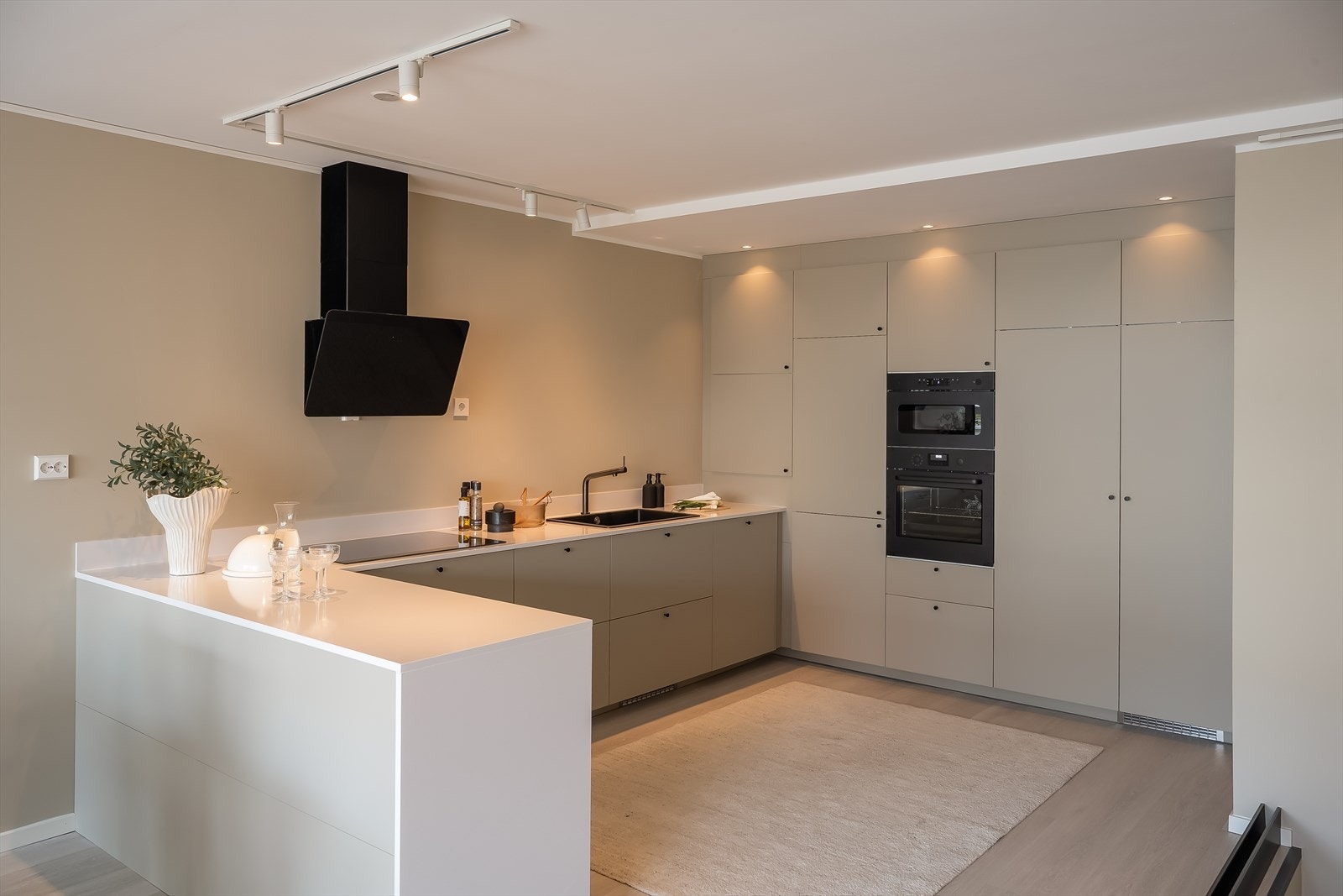 Kjøkkenet er et beige havstorp-kjøkken, med integrerte hvitevarer og eksklusiv benkeplate i stein. Galleribilde