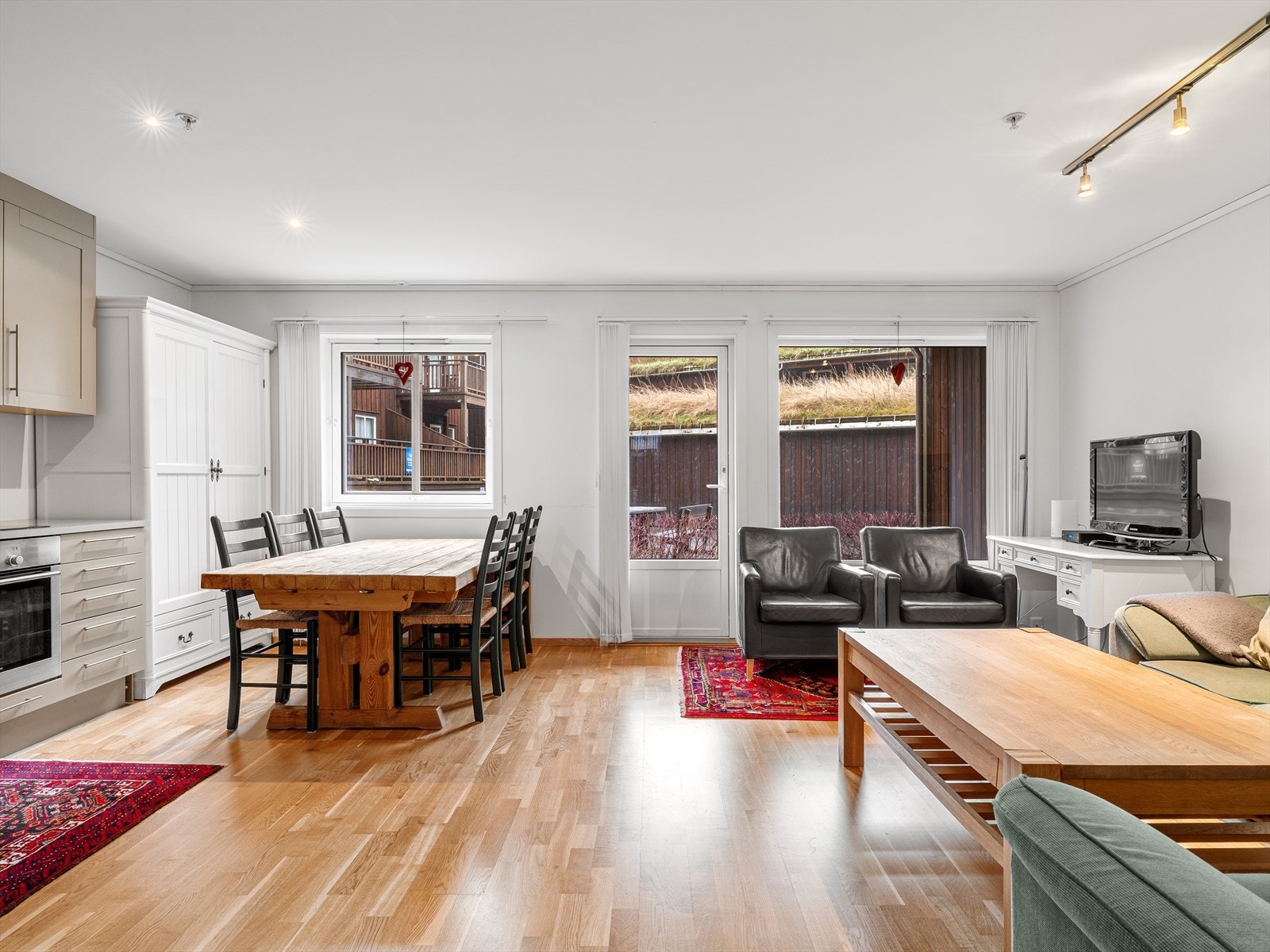 En lys og herlig stue med åpen kjøkkenløsning, hvor det er plass til hele familien. Sofagruppe, godstoler og langbord. Galleribilde