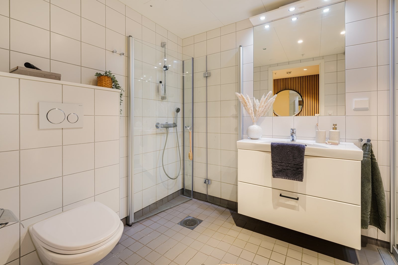 Her er det pene hvite baderomsmøbler, speil over vask og vegghengt toalett Galleribilde