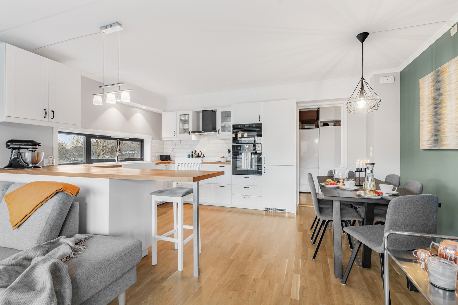 Stue og kjøkken ligger i en åpen løsning, adskilt av en praktisk kjøkkenhalvøy Galleribilde