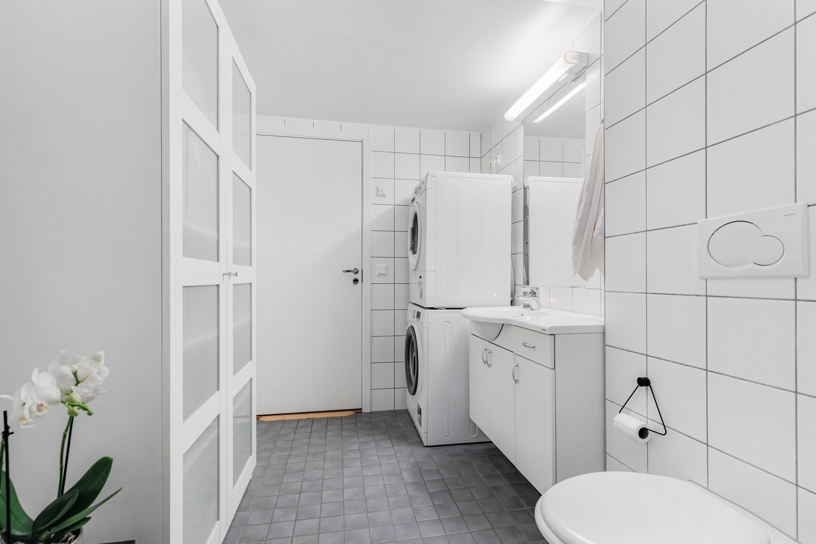 Badet har sanitærutstyr som veggmontert toalett, dusjnisje, servant og opplegg til vaskemaskin Galleribilde