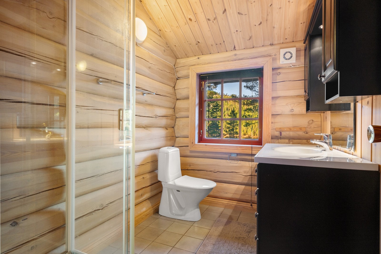 Badet er fra 2007 og er innredet med dusjkabinett, gulvmontert toalett og servantinnredning med nedsenket servant og speil. Galleribilde