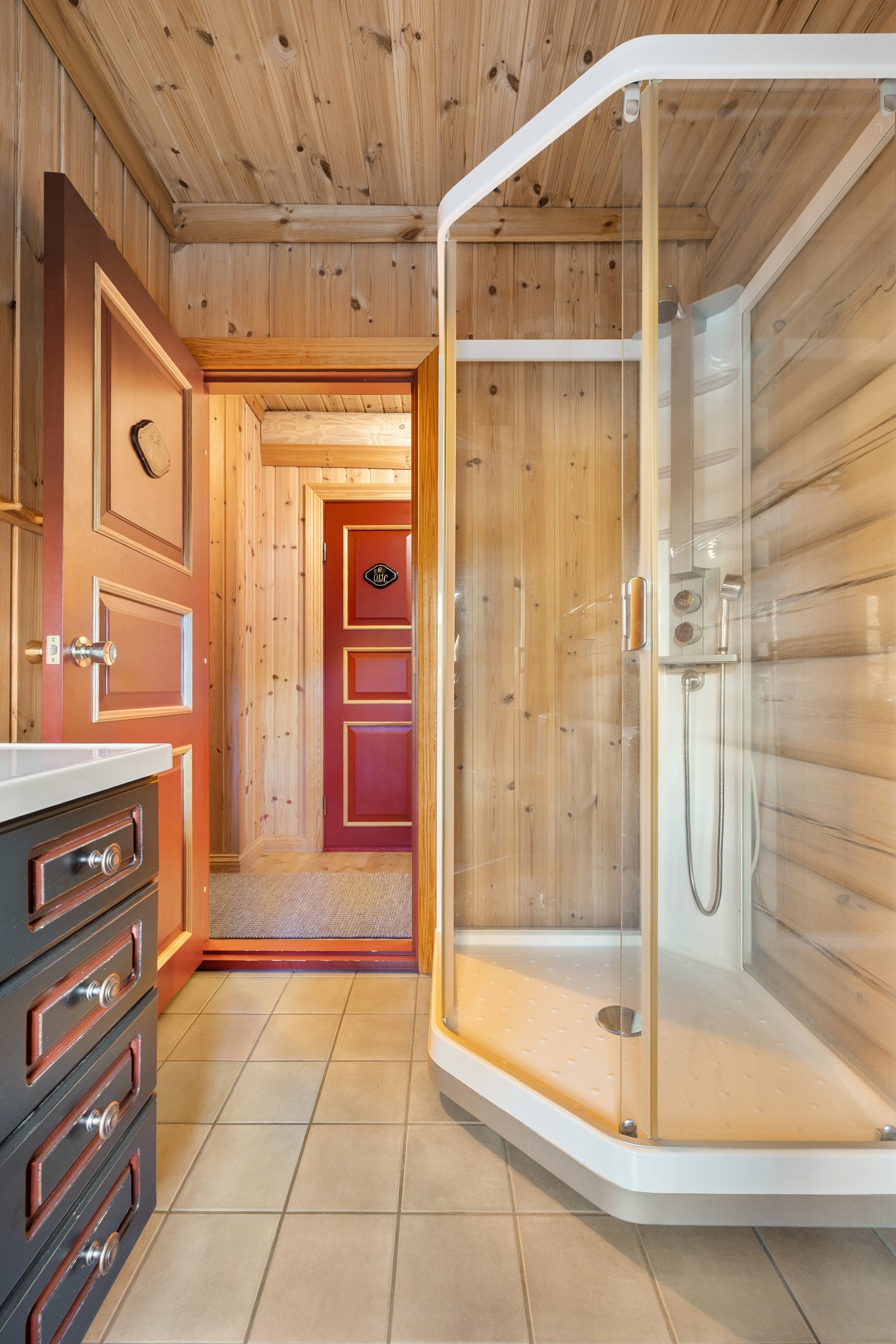 Rommet har flislagt gulv med elektriske varmekabler som gir god komfort, og vegger i en kombinasjon av laftet tømmer og trepanel. Galleribilde