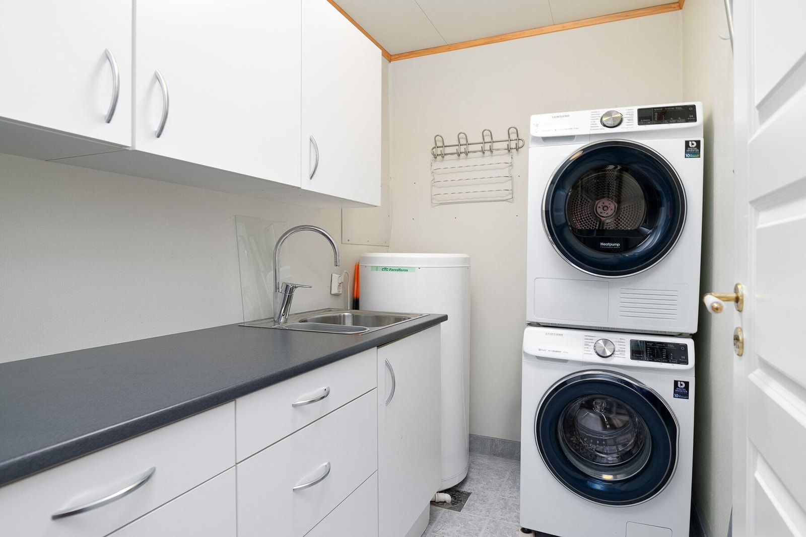 Praktisk separat vaskerom med opplegg for vaskemaskin og tørketrommel, samt innredning med vask. Galleribilde