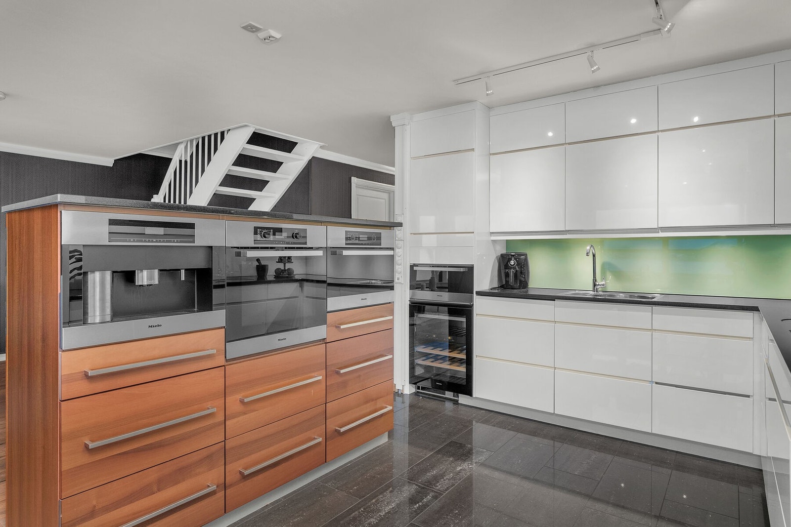 Kjøkkenet er rikelig utstyrt med integrerte hvitevarer som koketopp, komfyr, micro, kaffemaskin, vinskap, oppvaskmaskin og kjøleskap. Galleribilde