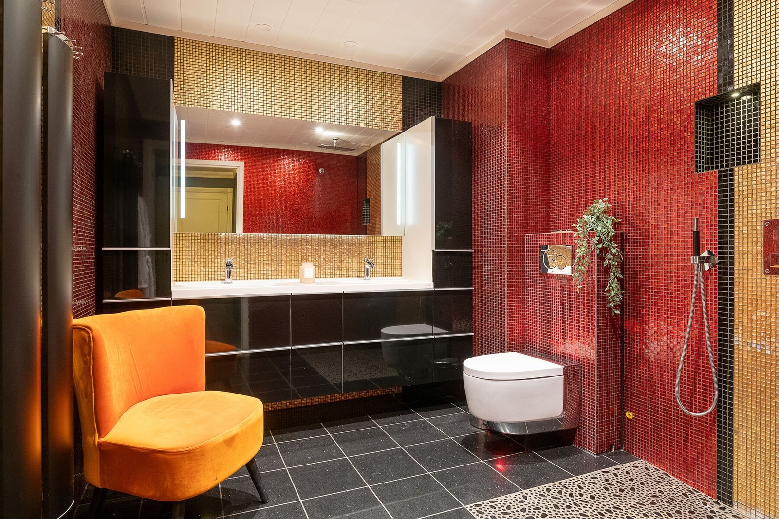 Romslig bad med dobbel servant på sort innredning, speil med lys, veggmontert wc og dusj med regnfall. Galleribilde