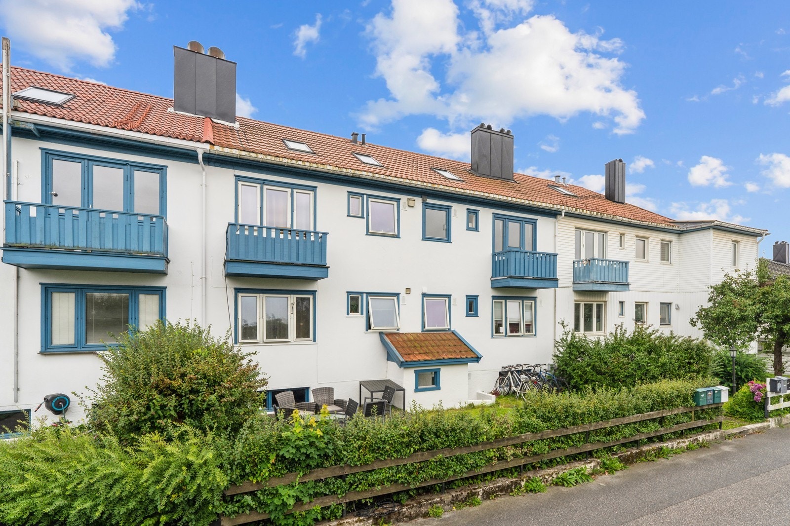 Velholdt fasade med balkonger og felles grøntområde i rolige omgivelser. Galleribilde