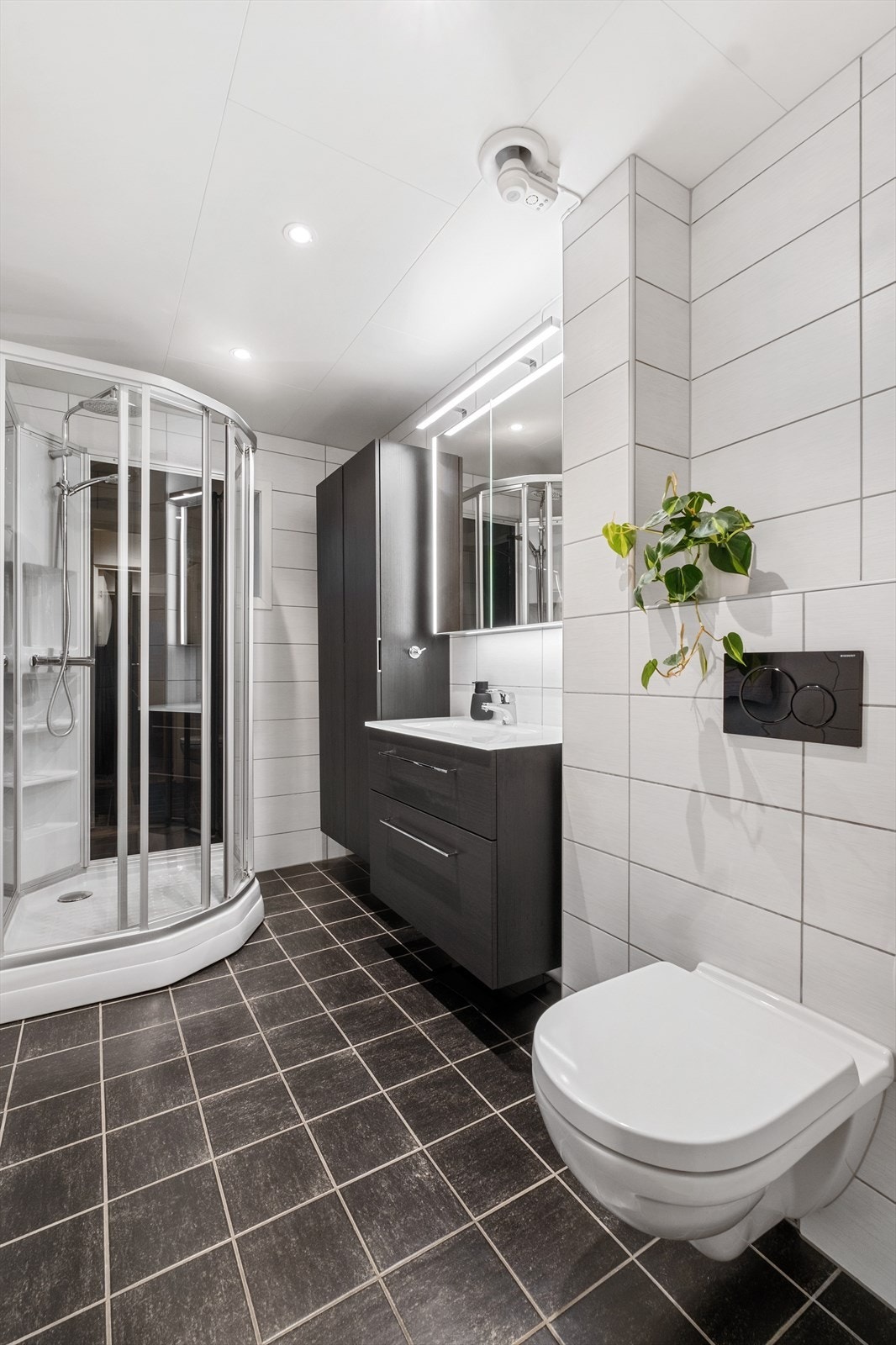 Badet er utstyrt med dusjkabinett, vegghengt toalett og en stilfull og moderne baderomsinnredning. Galleribilde