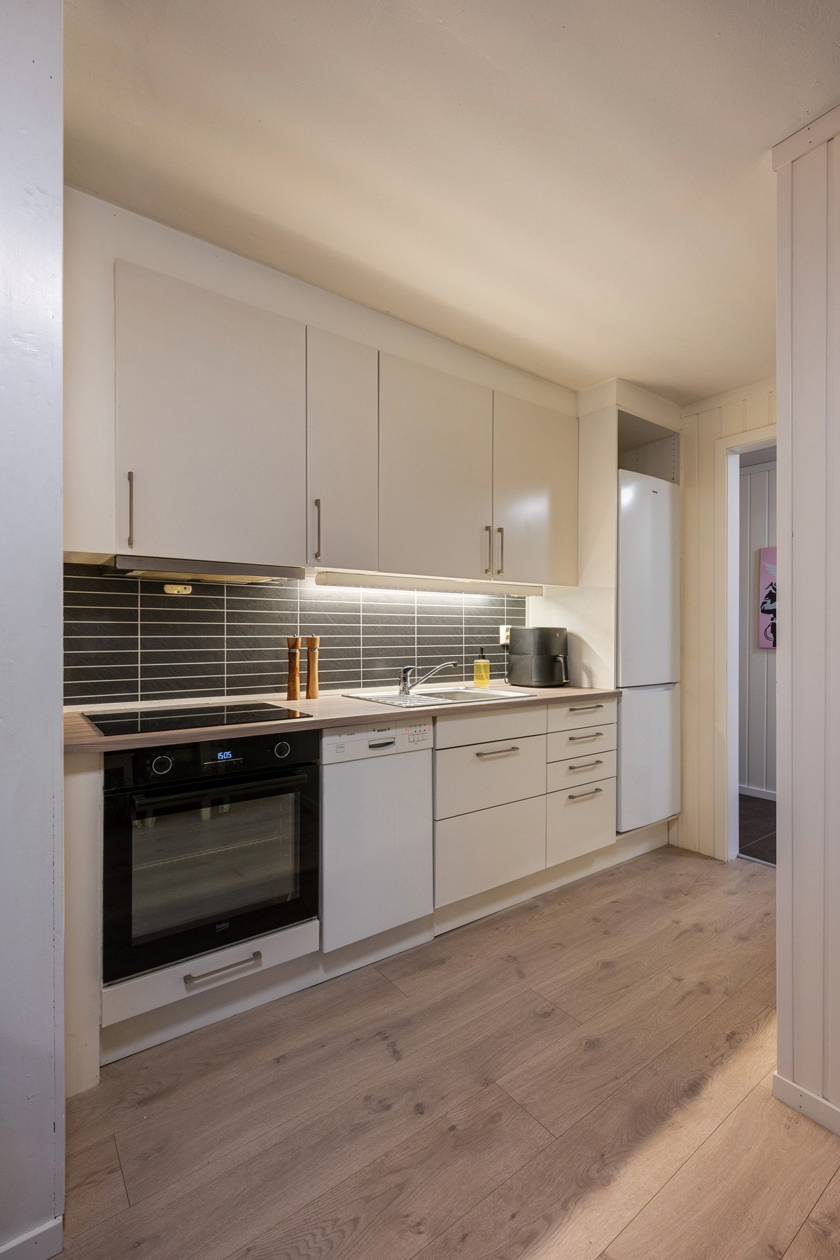 Hybelen har et funksjonelt kjøkken med glatte fronter. Kjøkkenet er utstyrt med integrerte hvitevarer som stekeovn og platetopp, samt opplegg og plass for frittstående smal oppvaskmaskin. Galleribilde