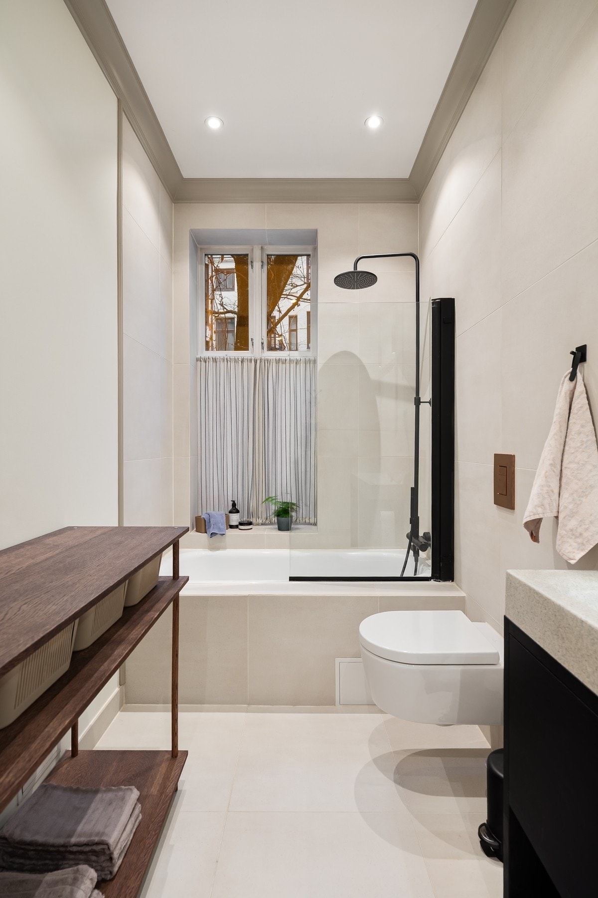 Dusj i badekar, dobbel servant i helstøpt plate og veggfestet klosett med innebygget sisterne. Galleribilde