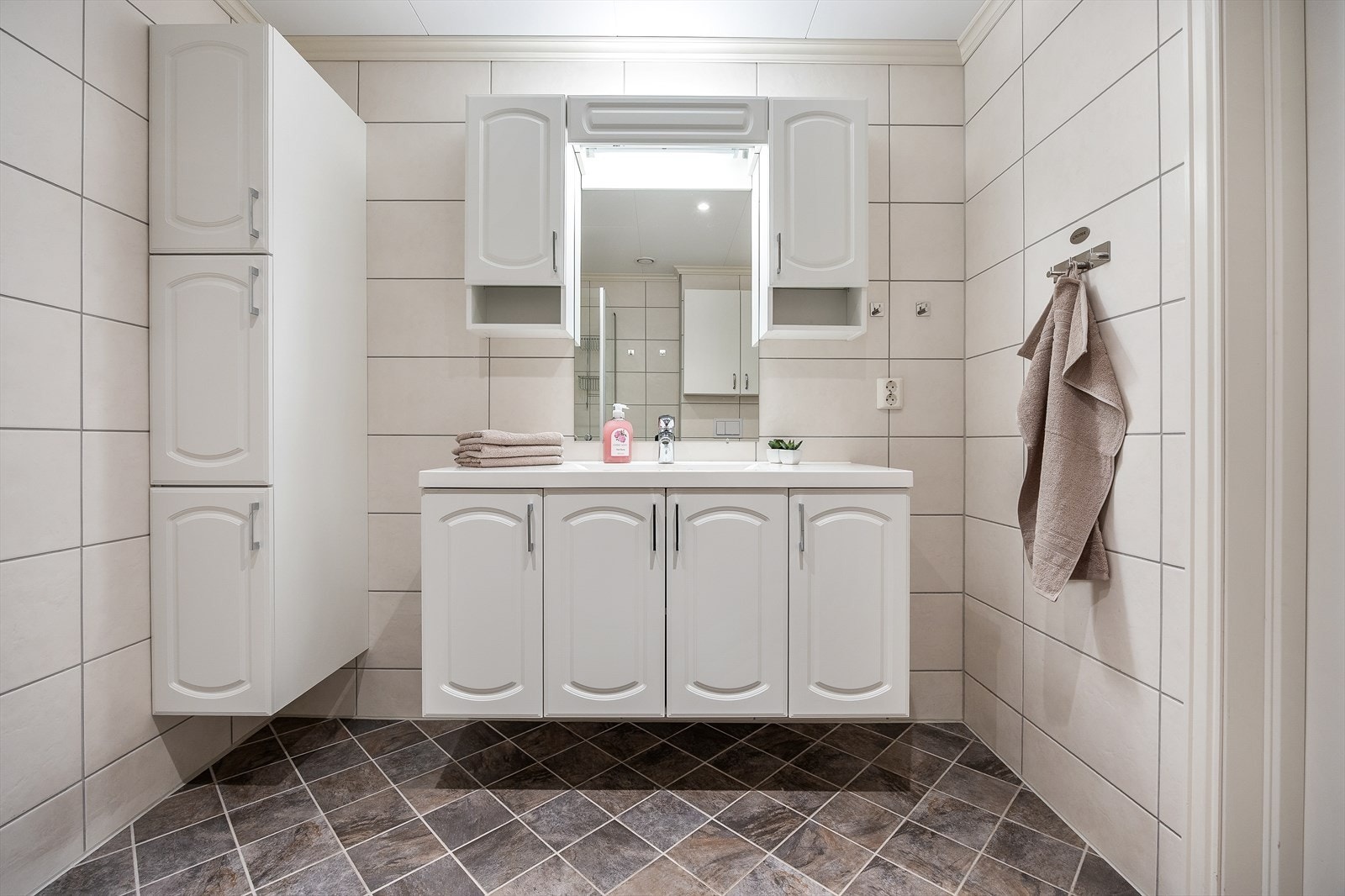 Speil og belysning i overkant av servant og oppbevaringsskap på vegg. Galleribilde