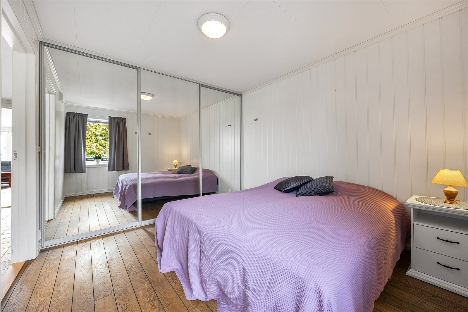 Hovedsoverommet har stor plass til dobbeltseng og tilhørende nattbord, samt tilgang til skyvedørsgarderobe med speilfronter. Galleribilde
