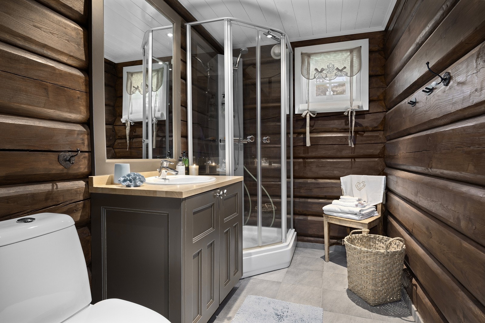 Baderom med flis på gulv og vegg. Baderomsinnredning bestående av dusjkabinett, toalett og servant. Galleribilde