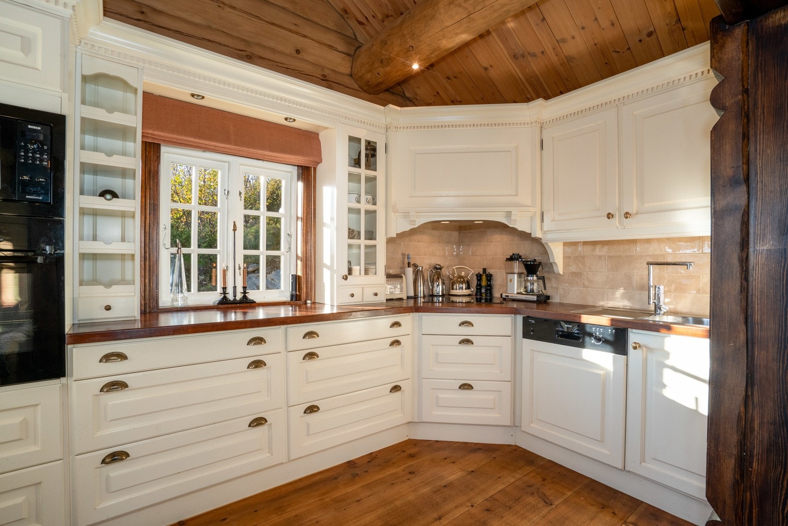 Innredningen har brede skuffer med lyse, profilerte fronter og heltre benkeplater. Mellom benkeplaten og overskapene er det nydelige fliser som kler innredningen godt. Galleribilde