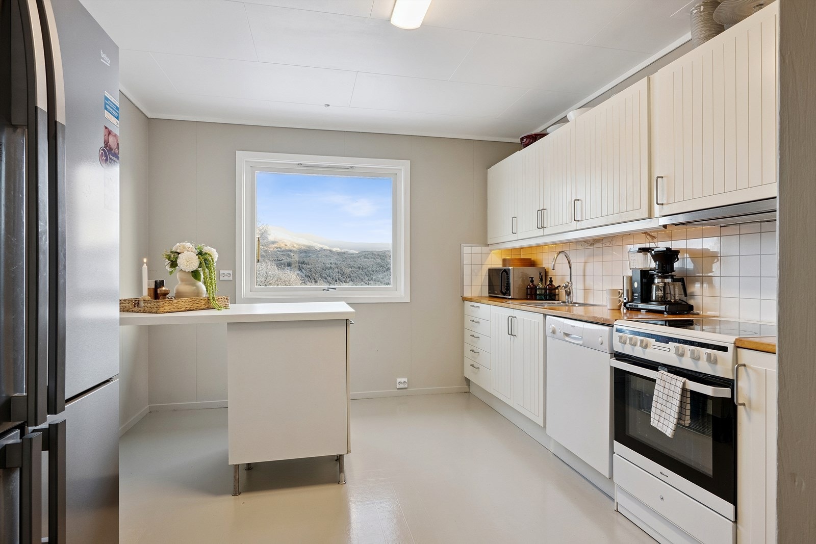 Kjøkken med malte profilerte fronter og lakkert heltre benkeplate med kitchenboard mellom benkeplate og overskap. Galleribilde