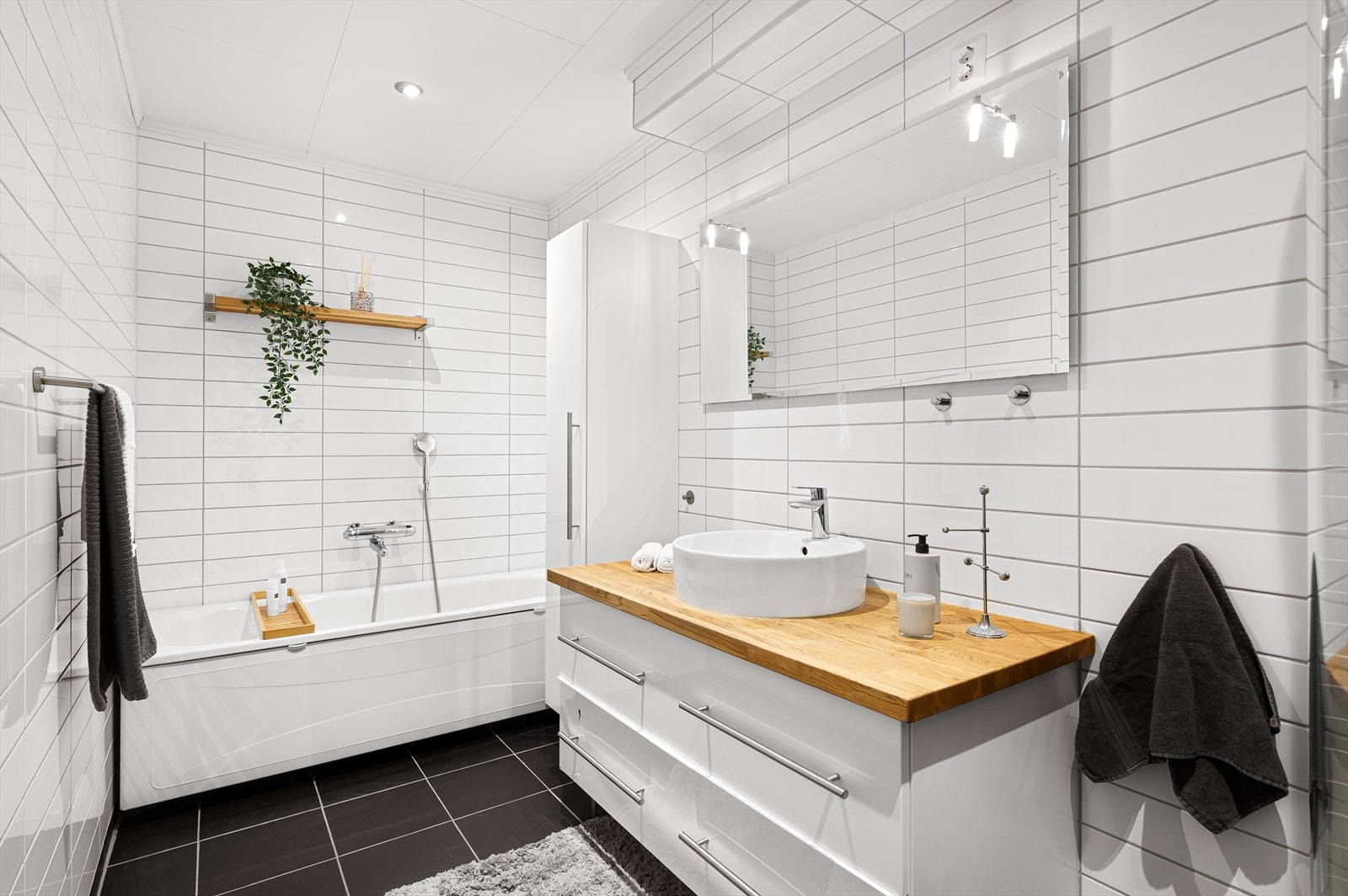 Flott bad med vegghengt klosett, innredning med servant, dusj med glassdører og badekar. Galleribilde