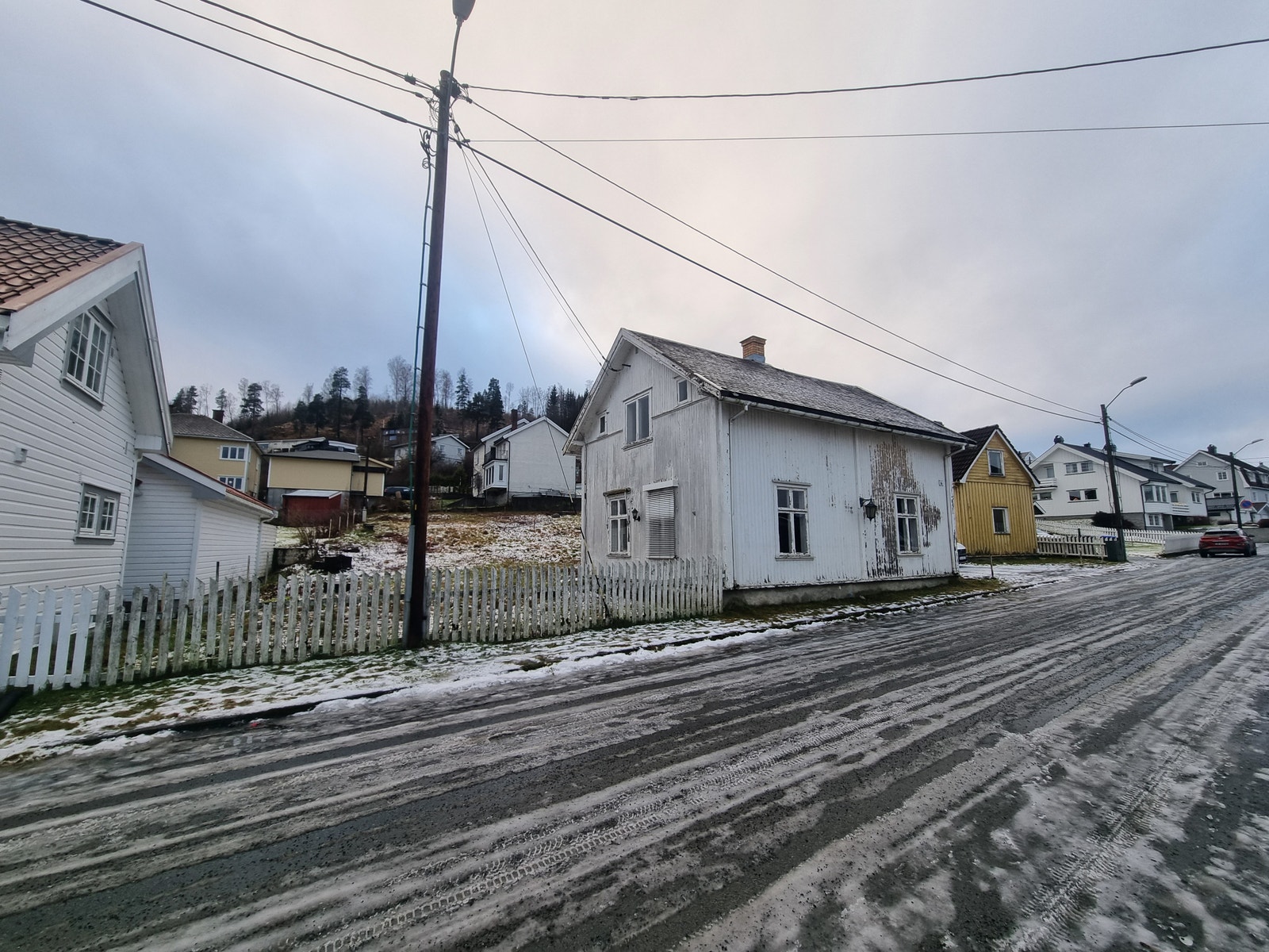 Bilde tatt fra veien nedenfor tomta. Hvit bolig skal renoveres. Galleribilde