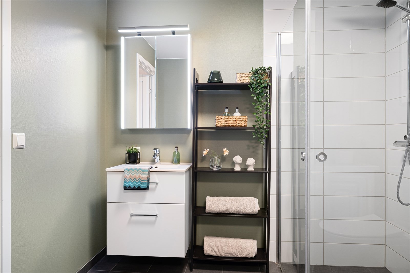 Innredningen består av et vegghengt toalett, servant med underskuffer, dusjhjørne og speil med integrert belysning og skap. Galleribilde