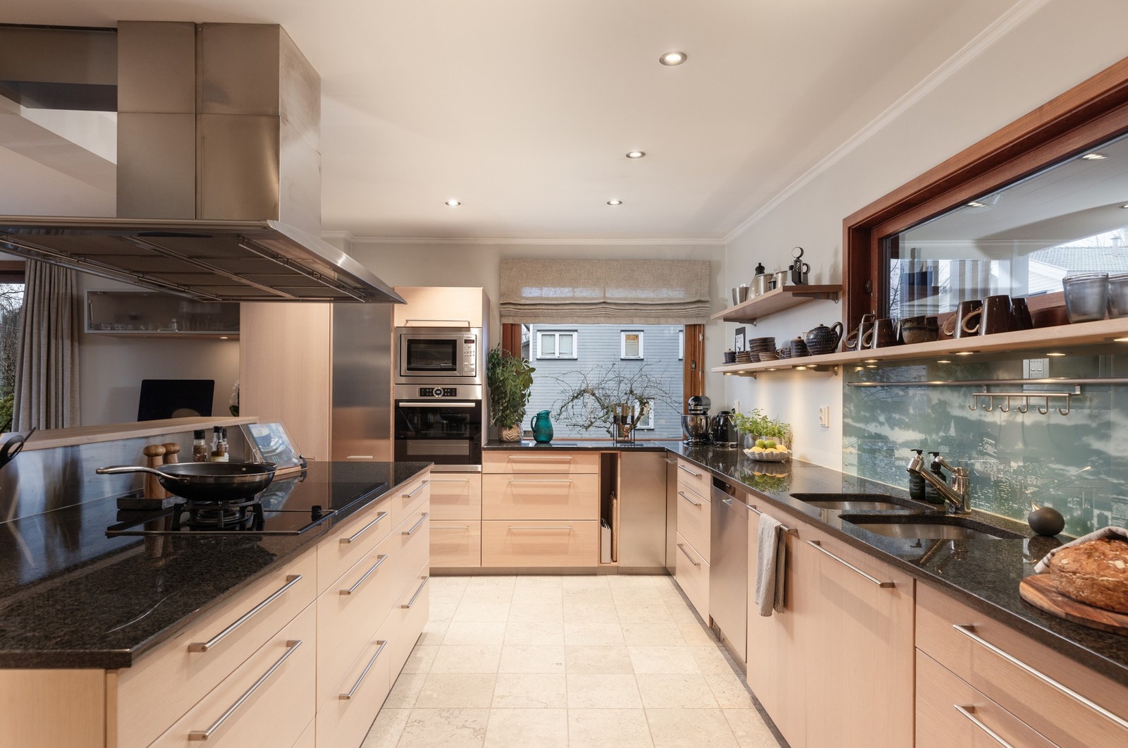 Kjøkkeninnredningen har lyse, glatte fronter, benkeplater av granitt og dobbel oppvaskkum i rustfritt stål Galleribilde