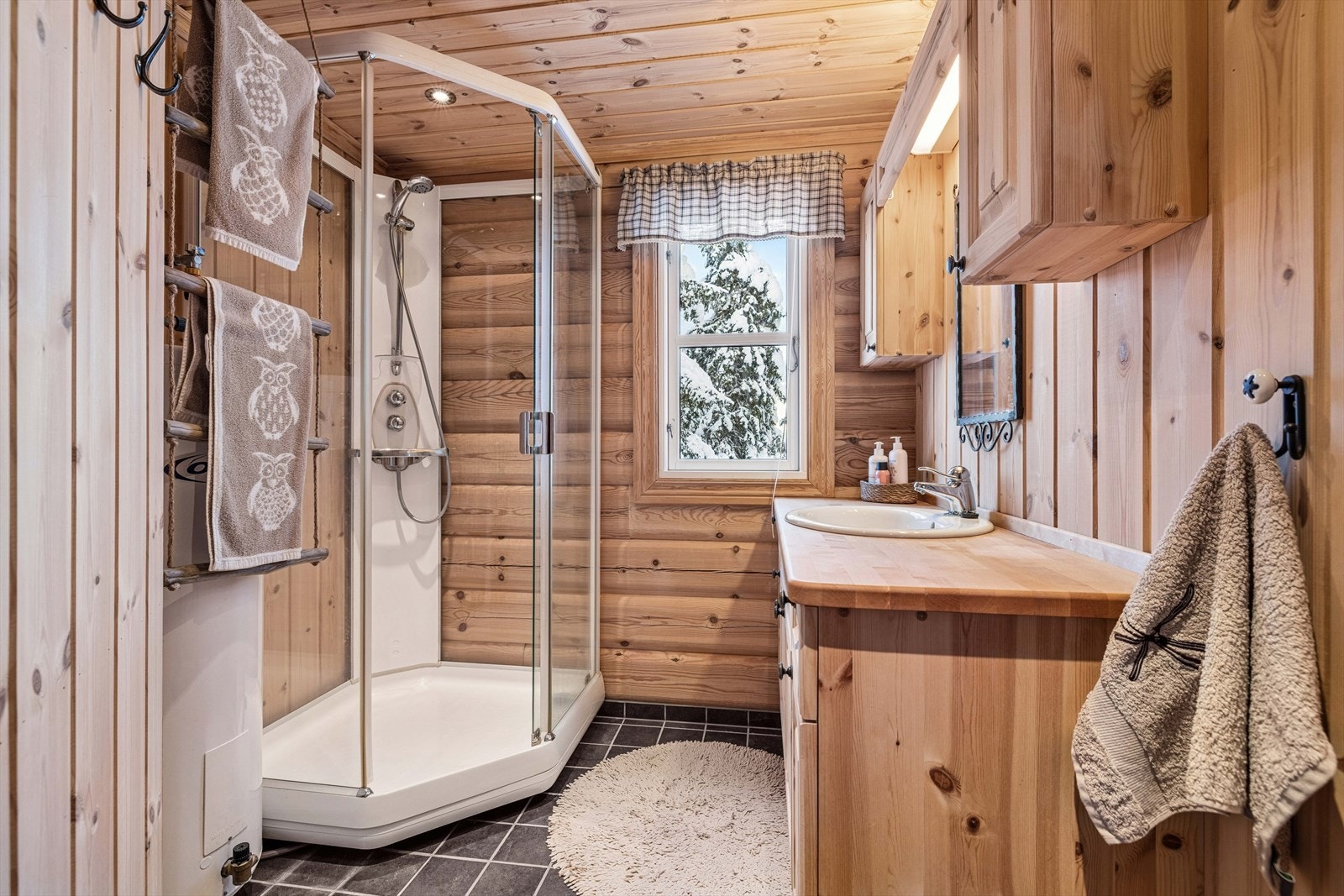 Badet har vegger som er kombinert med panel og tømmer og flislagt gulv med elektriske varmekabler. Rommet er innredet med servant og dusjkabinett. Galleribilde