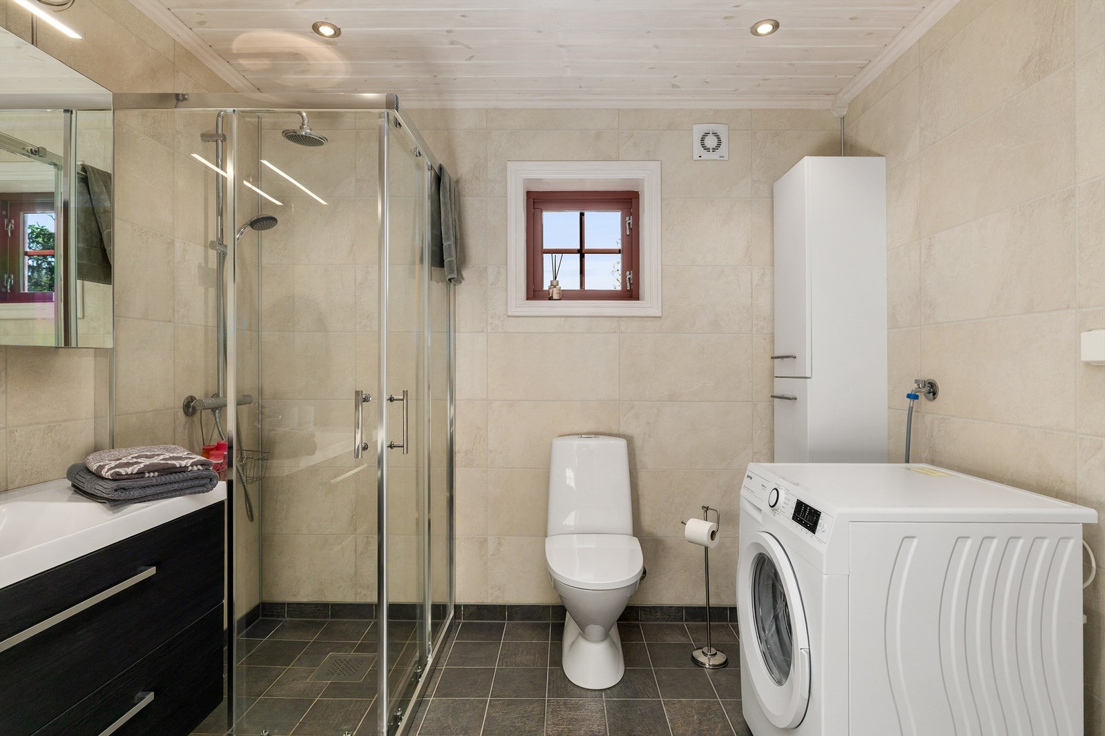 Badet har dusjnisje med glassdører og opplegg for vaskemaskin. Galleribilde