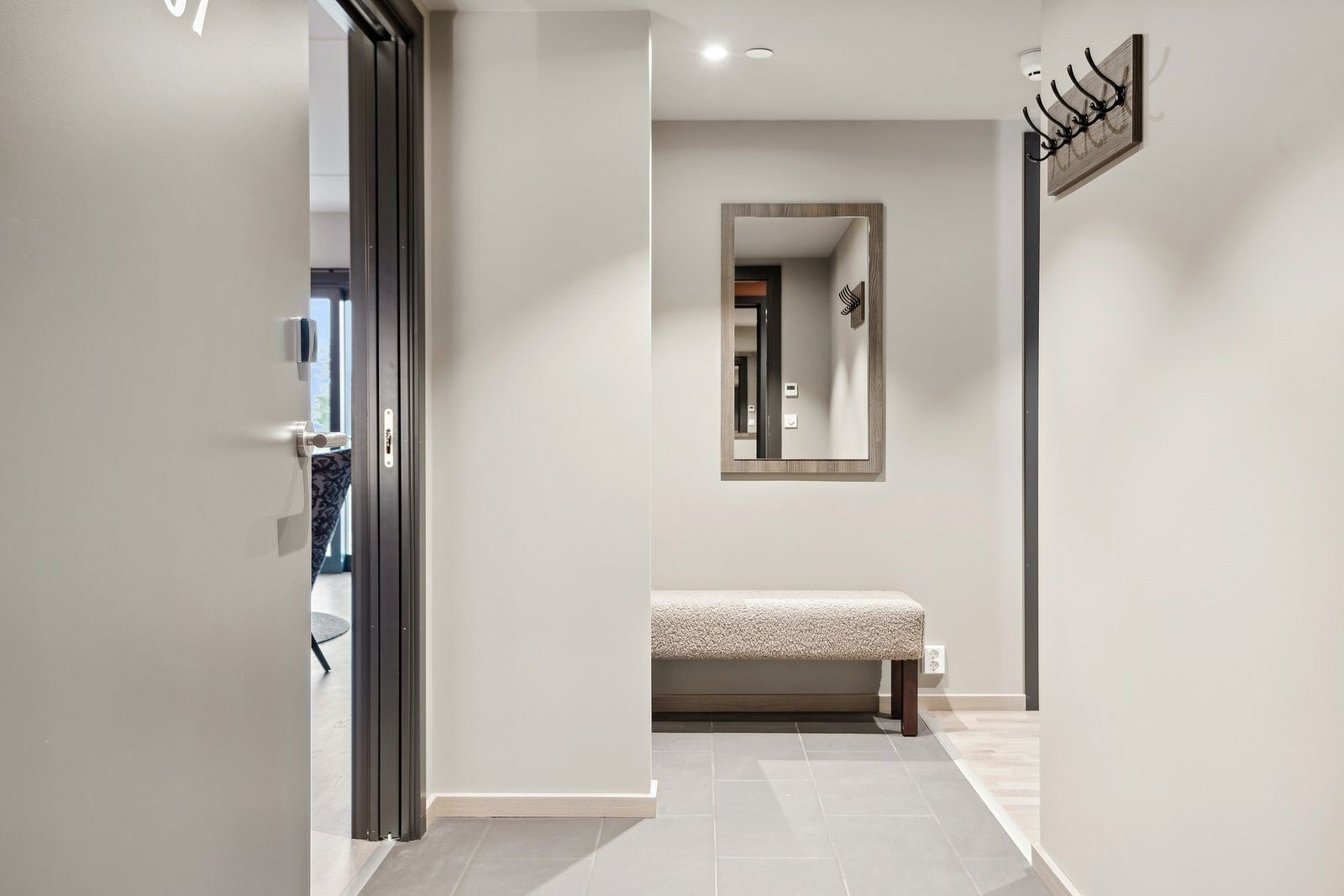 Velkommen inn! Lysmalt entré med praktiske fliser på gulv med gulvvarme, enkel møblering med speil, knaggrekke, benk samt garderobeskap. Det er downlightsbelysning i himling. Galleribilde