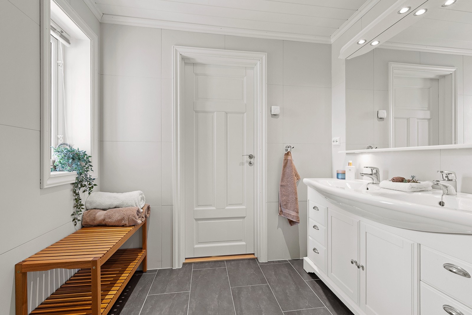 Badet fremstår moderne og gjennomført, med flislagte gulv med luftbåren gulvvarme, flislagte vegger og MDF-panel med downlights i himlingen. Galleribilde