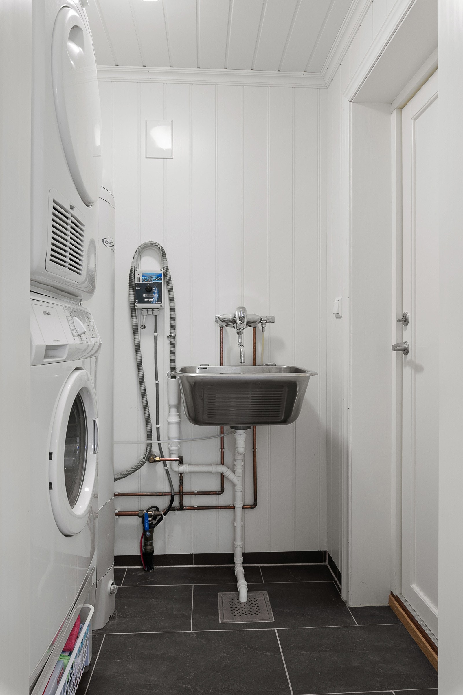 Fra badet ved entréen har du tilgang til et praktisk og funksjonelt teknisk rom. Her finner du utslagsvask og opplegg for både vaskemaskin og tørketrommel - en gjennomtenkt løsning som gjør hytta godt rustet for hverdagslige behov. Galleribilde