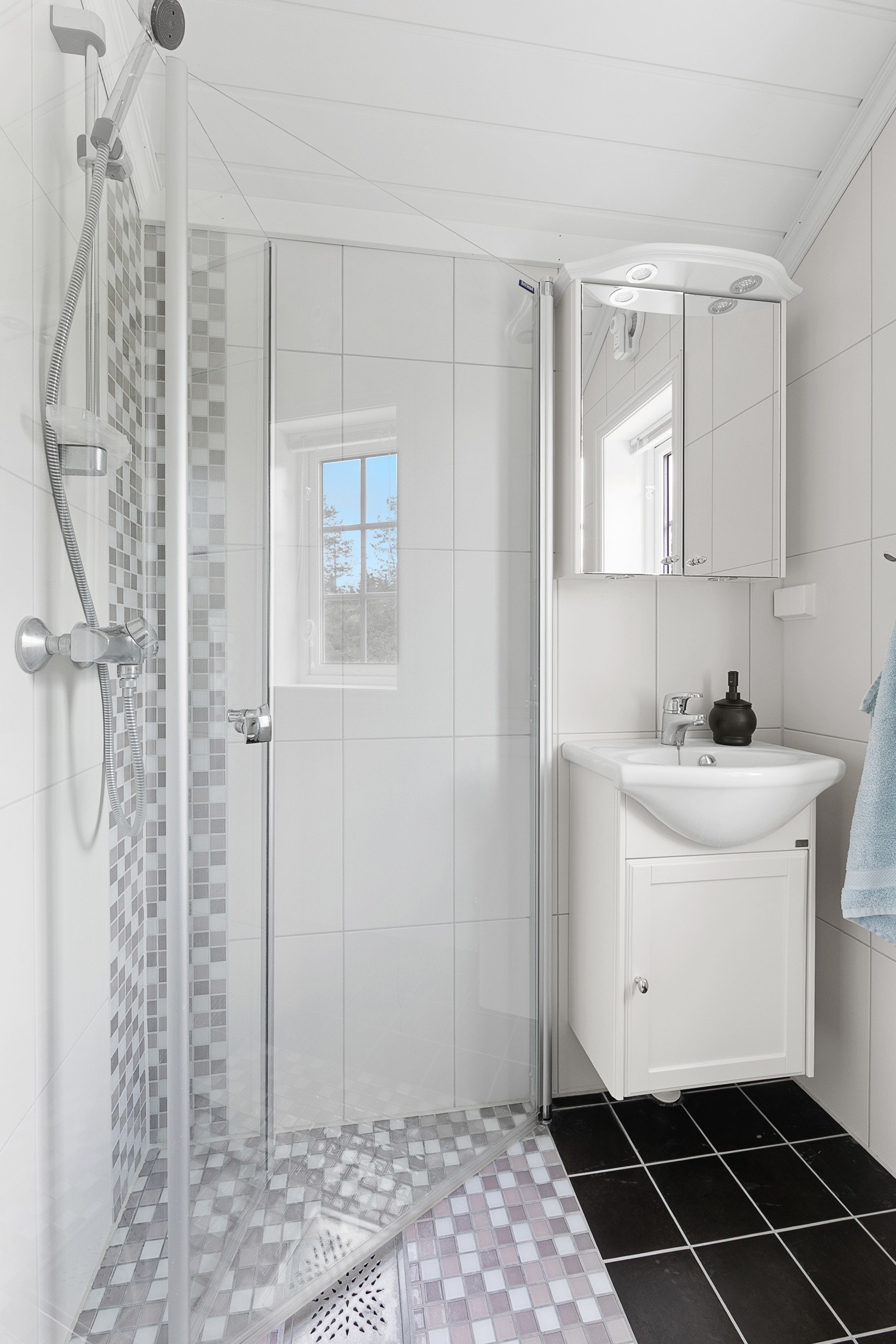 Rommet er innredet med heldekkende servant, speilskap med integrert lys, dusjhjørne med innfellbare glassdører og vegghengt toalett. Galleribilde