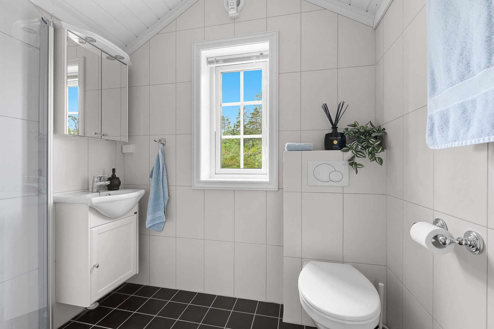 Et stilrent og moderne bad med flislagte gulv med luftbåren gulvvarme, flislagte vegger og MDF-panel i himling. Galleribilde