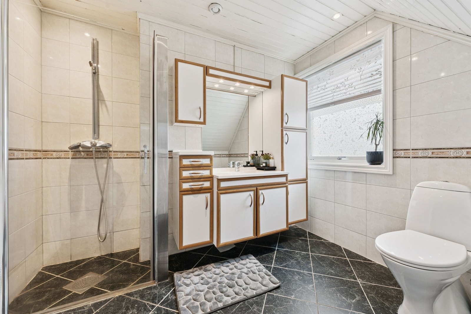 Baderom i 2.etg inneholder dusjnisje, vegghengt servant med under- og sideskap og WC. Det er varmekabler i gulv Galleribilde