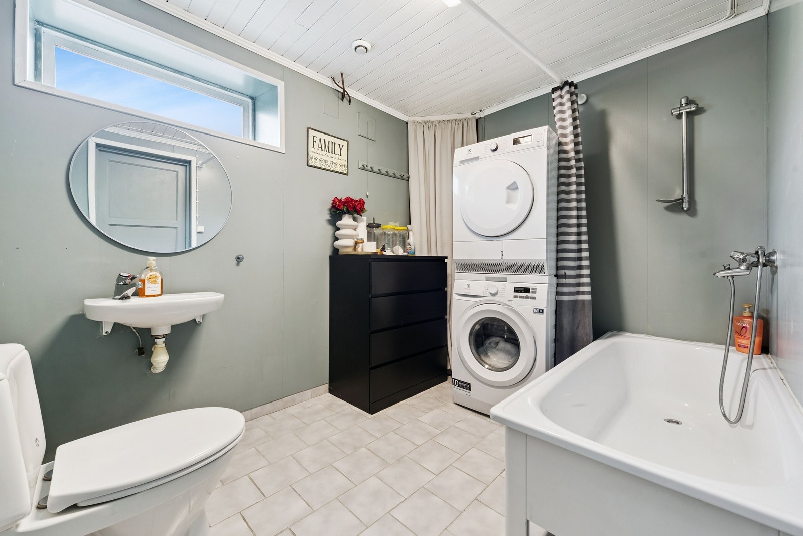 Vaskerom i kjeller inneholder badekar med dusjmuligheter, WC, servant og opplegg for tørke- og vaskemaskin Galleribilde