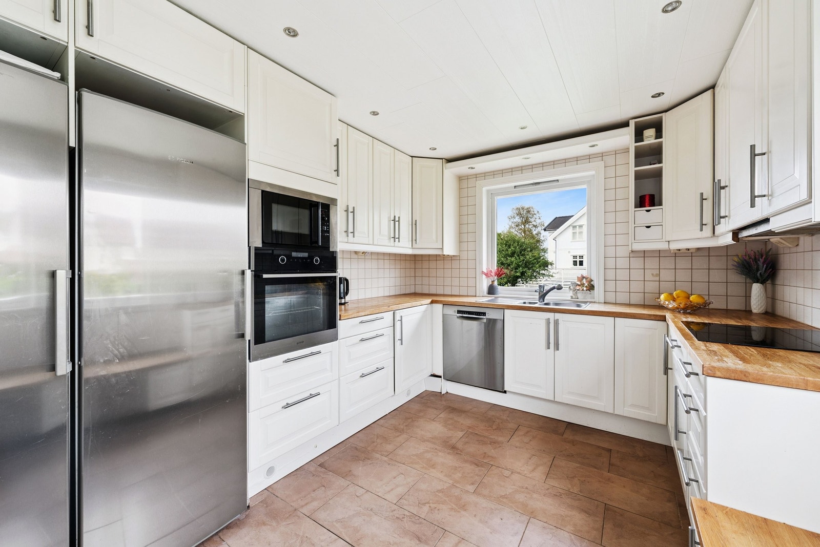 Velutstyrt kjøkken med kjøleskap, fryseskap, komfyr, oppvaskmaskin og platetopp Galleribilde