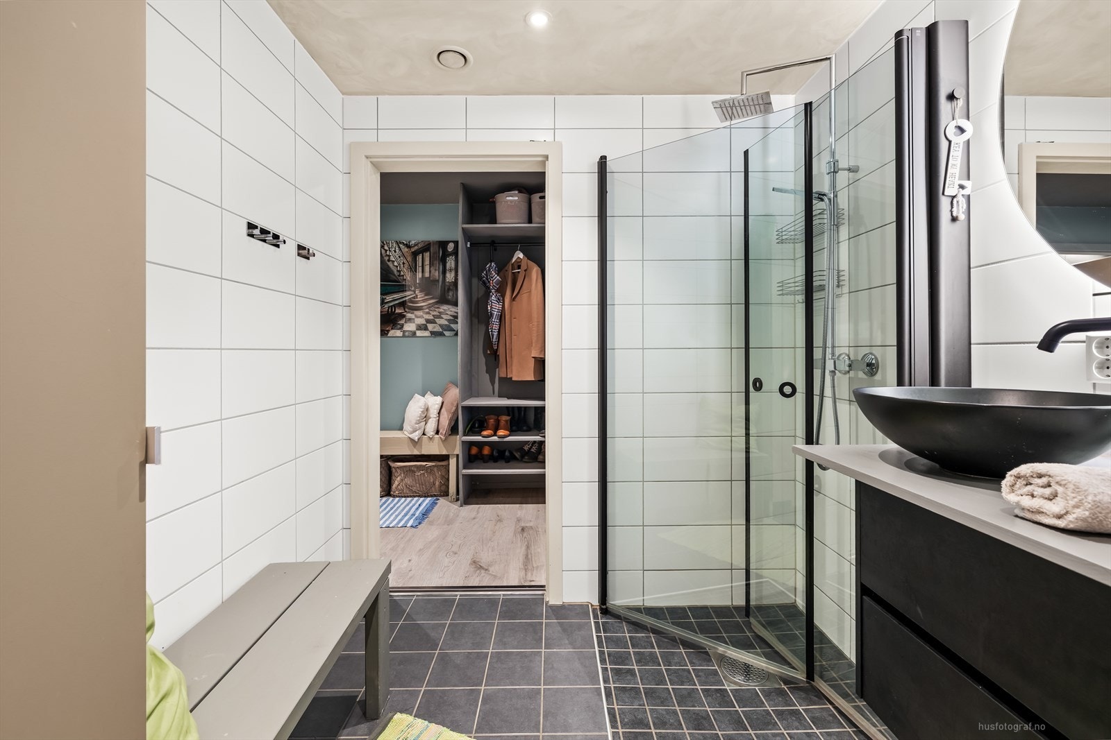 Innredning med to toppmonterte servanter, veggmontert toalett, dusjhjørne med glassvegger og opplegg for vaskemaskin. Galleribilde