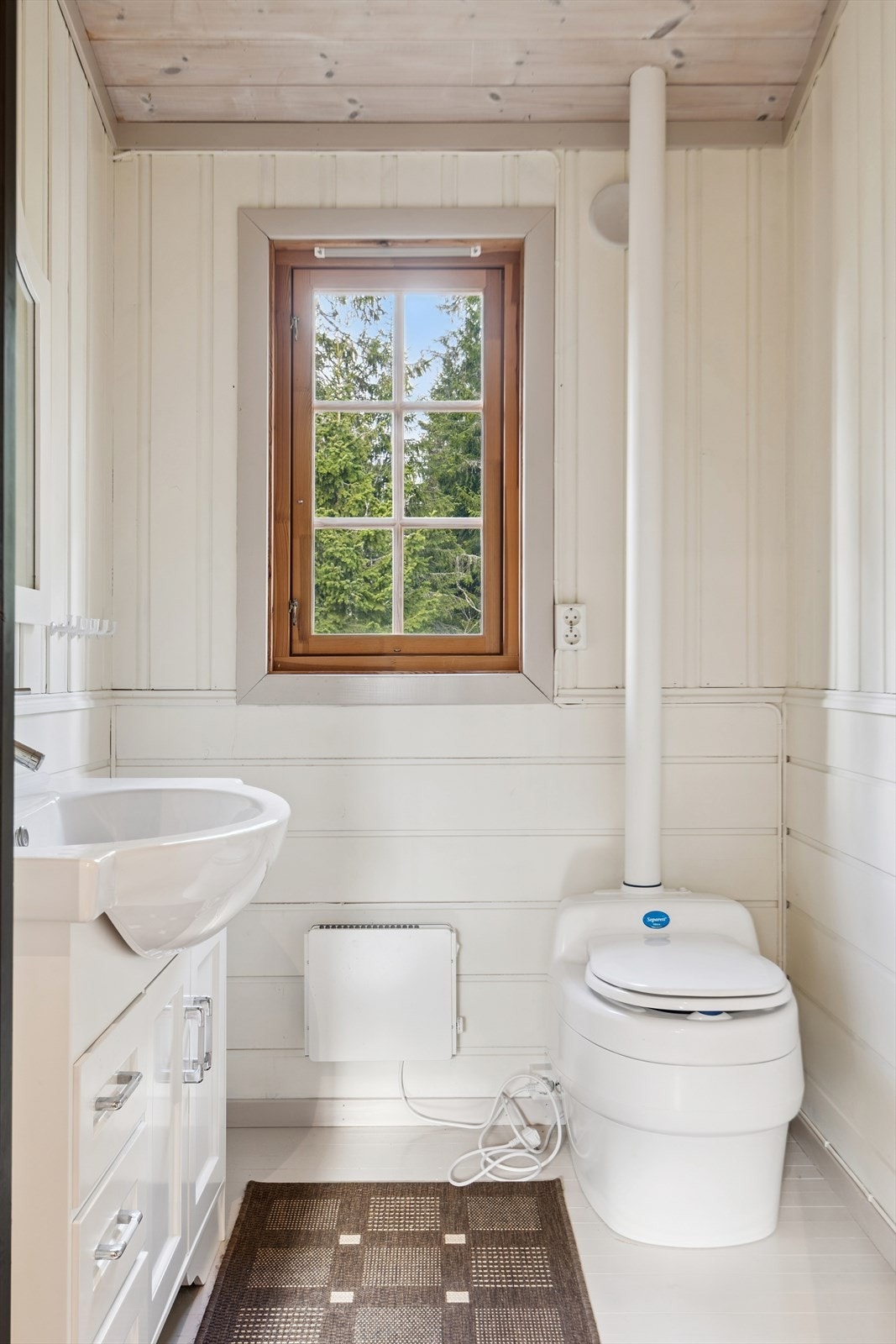 Praktisk toalattrom med servant i baderomsinnredning og gulvmontert snurretoalett. Galleribilde