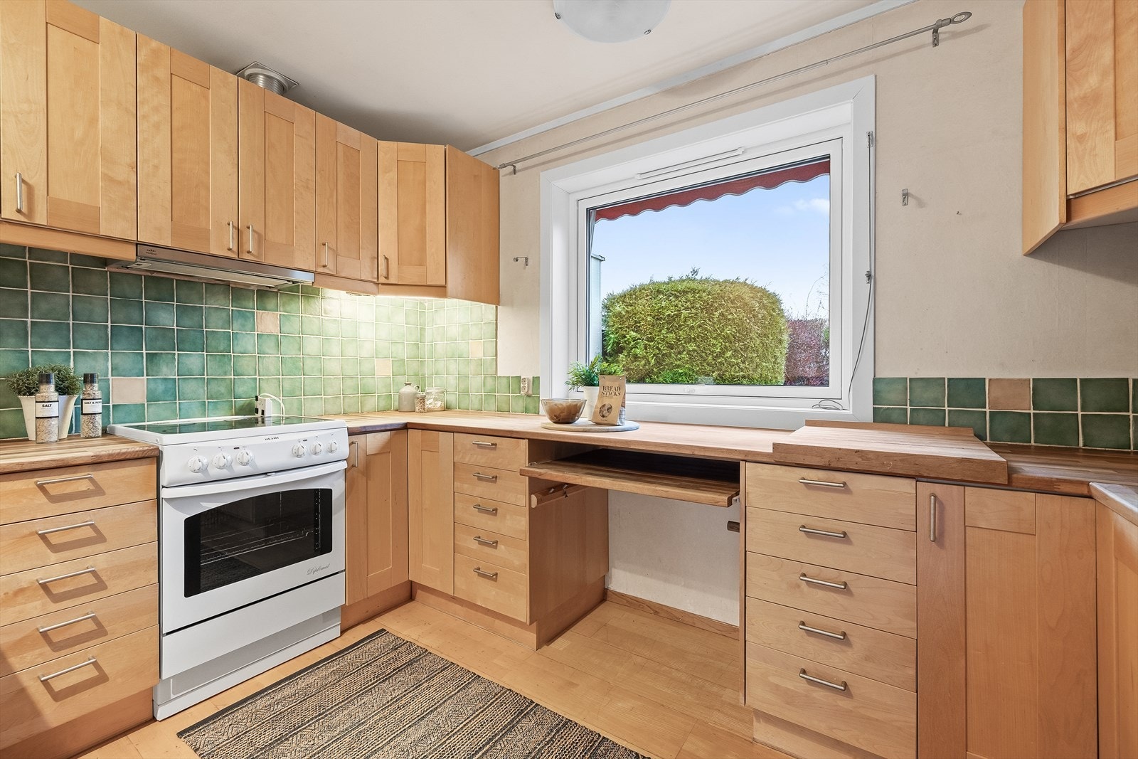 Vindu mot hagen gir et trivelig lysinnslipp og en lun atmosfære under matlagingen. Galleribilde