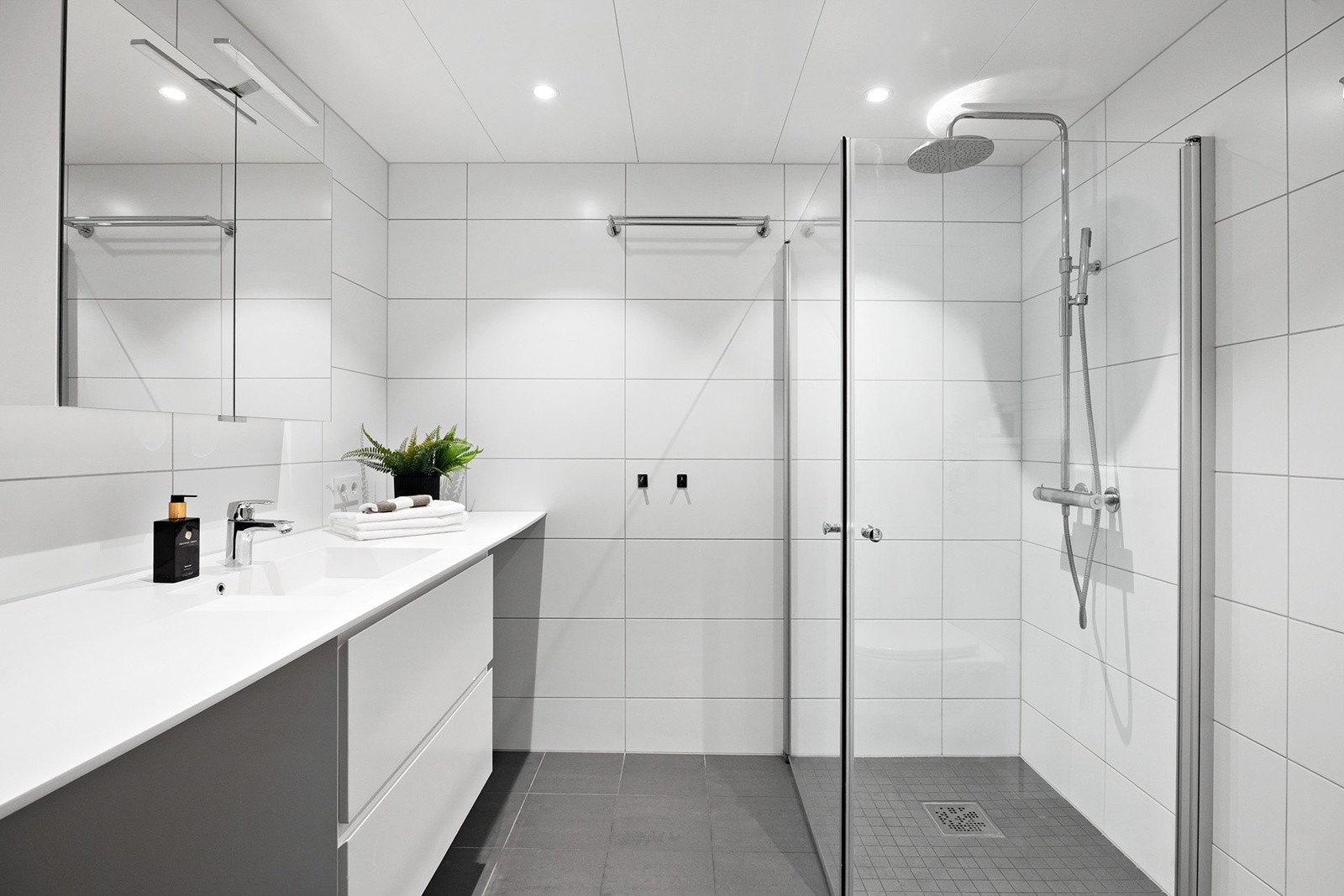 Badet har innredning med nedfelt servant, speilskap m/belysning, veggmontert toalett, dusjvegger/hjørne og opplegg for vaskemaskin. Galleribilde